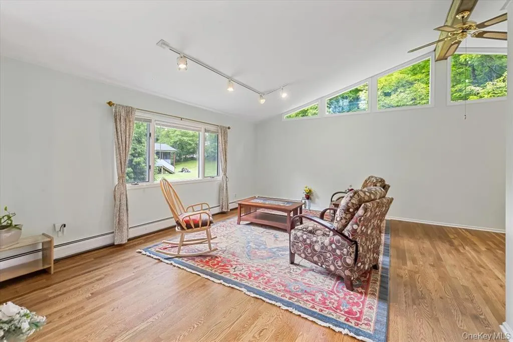 Sitting room with rail lighting, lofted ceiling, and light wood-type flooring Sitting room with rail lighting, lofted ceiling, and light wood-type flooring