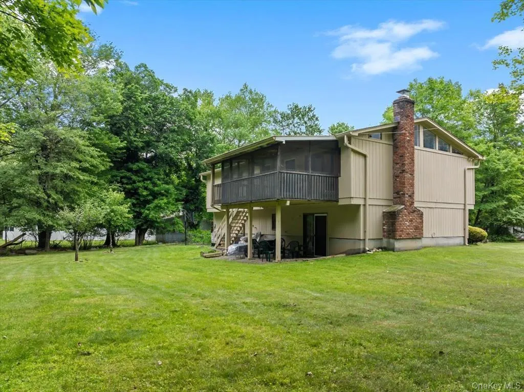 Back of house featuring a sunroom, stairs, a yard, a chimney, and a wooden deck Back of house featuring a sunroom, stairs, a yard, a chimney, and a wooden deck