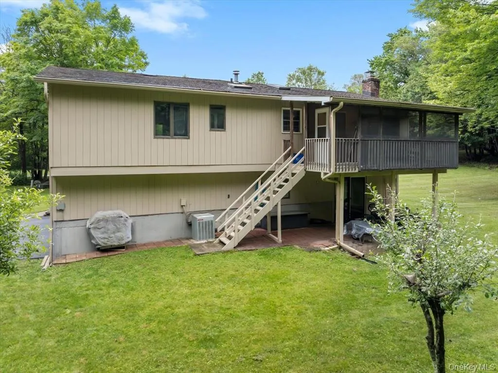 Rear view of property with stairs, a yard, a wooden deck, a chimney, and a sunroom Rear view of property with stairs, a yard, a wooden deck, a chimney, and a sunroom