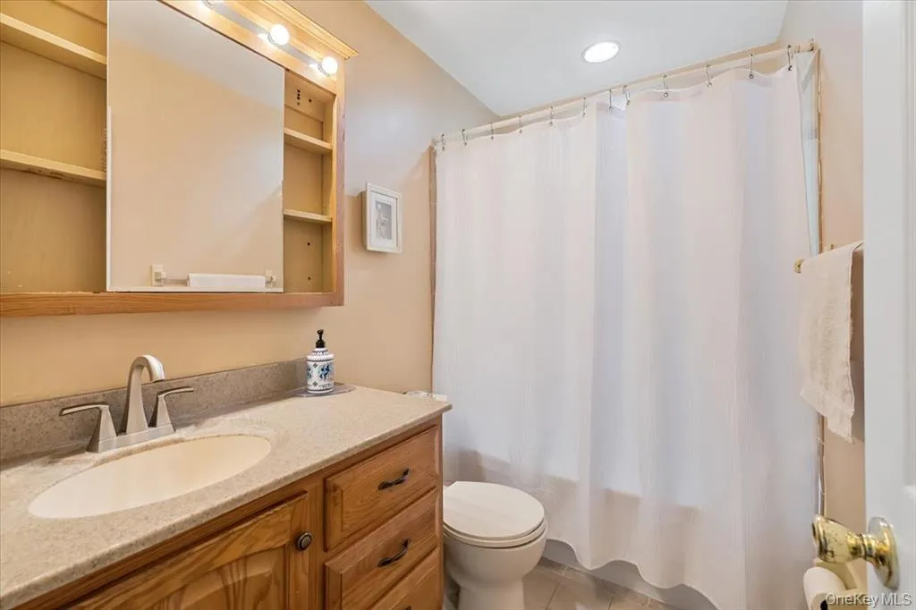 Full bath with shower / bath combination with curtain, vanity, and light tile patterned flooring Full bath with shower / bath combination with curtain, vanity, and light tile patterned flooring