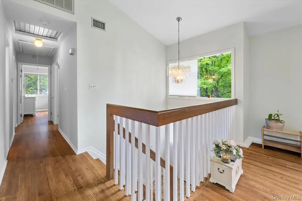 Corridor with attic access, vaulted ceiling, an upstairs landing, wood finished floors, and a chandelier Corridor with attic access, vaulted ceiling, an upstairs landing, wood finished floors, and a chandelier