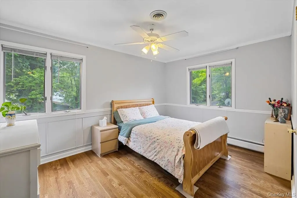 Bedroom featuring baseboard heating, light wood-style floors, crown molding, and ceiling fan Bedroom featuring baseboard heating, light wood-style floors, crown molding, and ceiling fan