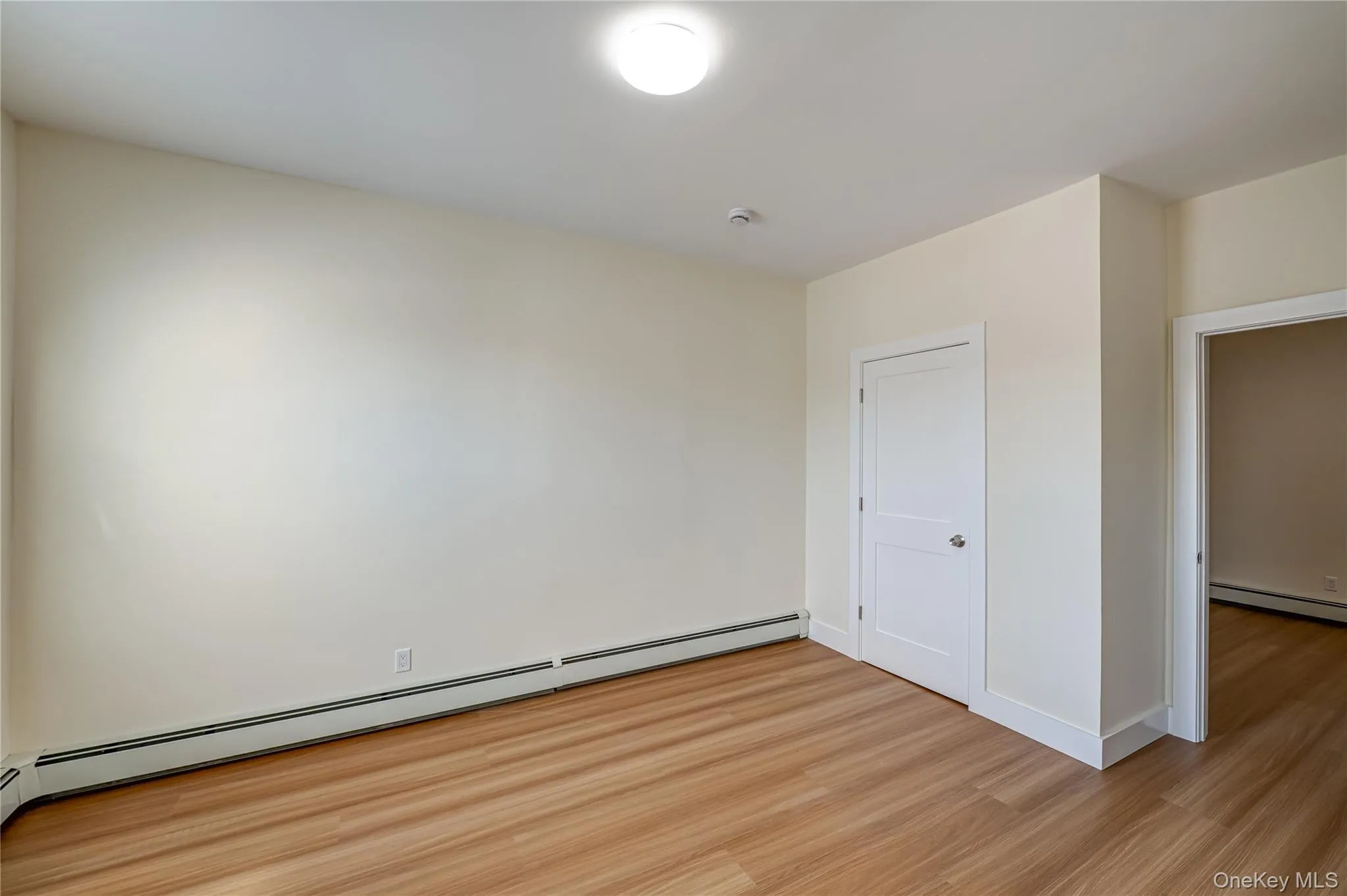 Unfurnished bedroom featuring a baseboard radiator and wood finished floors Unfurnished bedroom featuring a baseboard radiator and wood finished floors