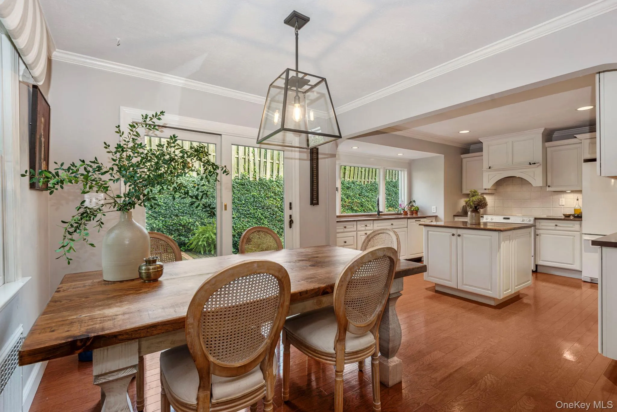 Dining room with arched entrance to kitchen and sliders to the deck and gardens. Dining room with arched entrance to kitchen and sliders to the deck and gardens.