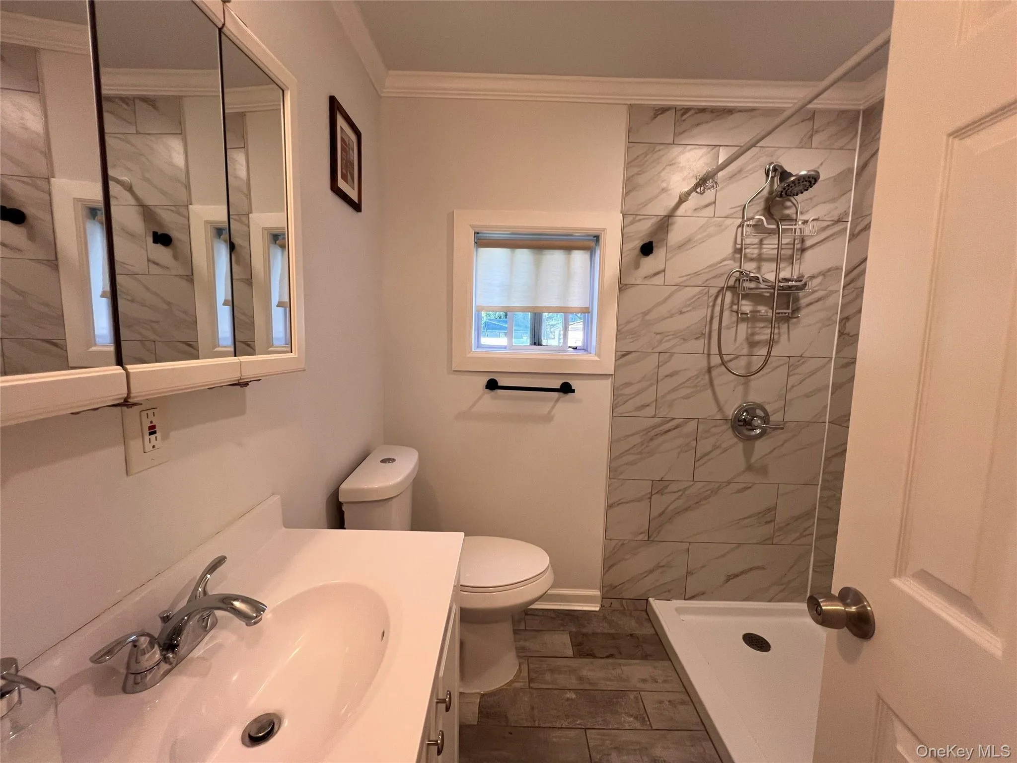 Updated bathroom featuring a shower with full height tile surround, wall mounted shower system, and tile flooring Updated bathroom featuring a shower with full height tile surround, wall mounted shower system, and tile flooring