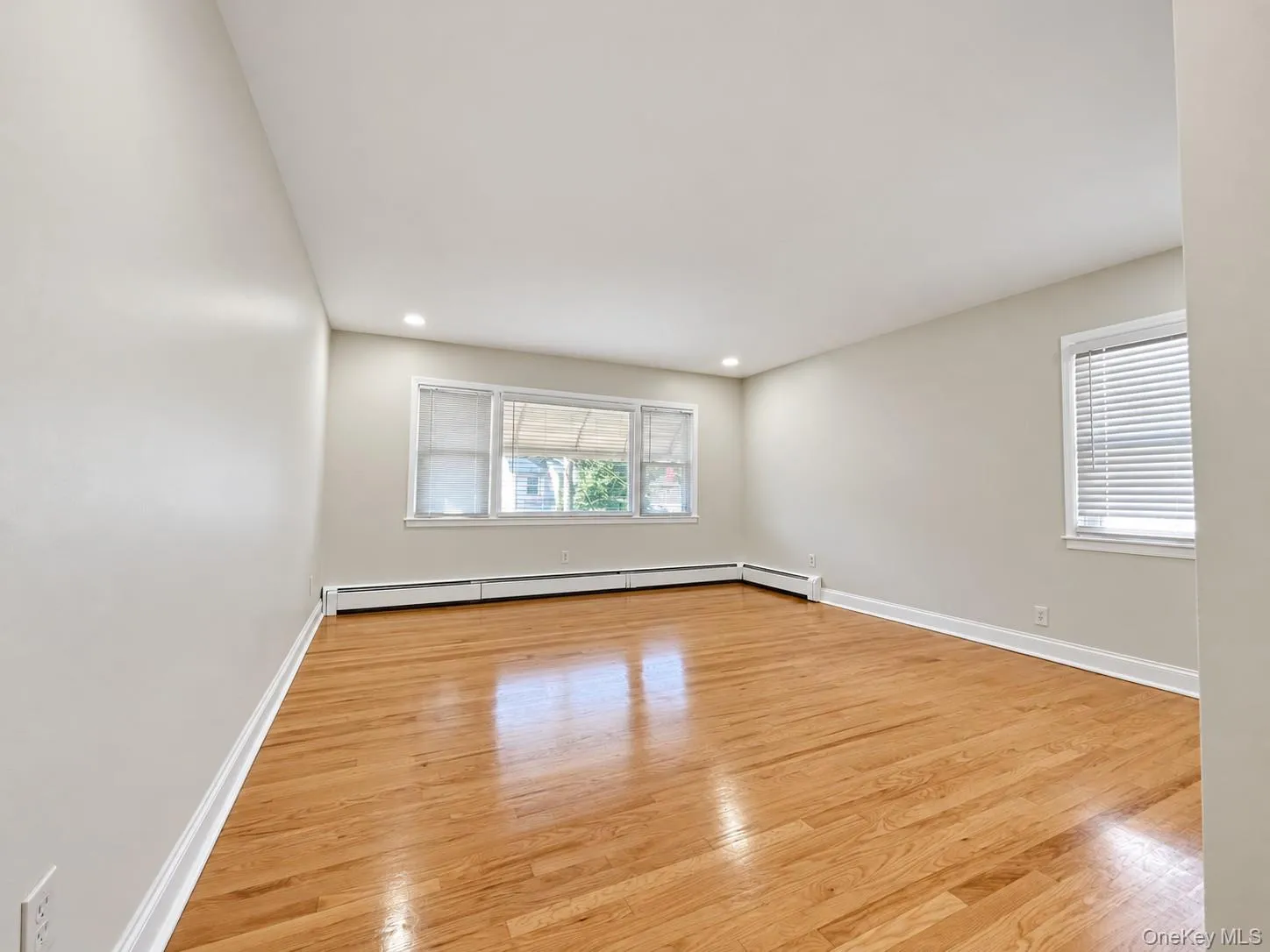 Wood-finish flooring, recessed lighting, and multiple windows with horizontal blinds Wood-finish flooring, recessed lighting, and multiple windows with horizontal blinds