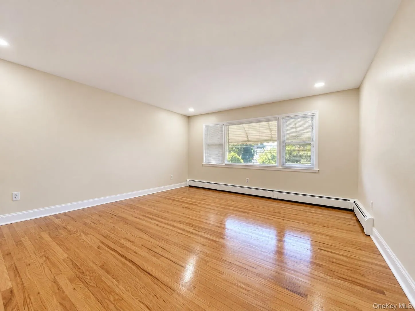 Hardwood flooring, recessed lighting, neutral wall tones, white trim, and a window with blinds Hardwood flooring, recessed lighting, neutral wall tones, white trim, and a window with blinds