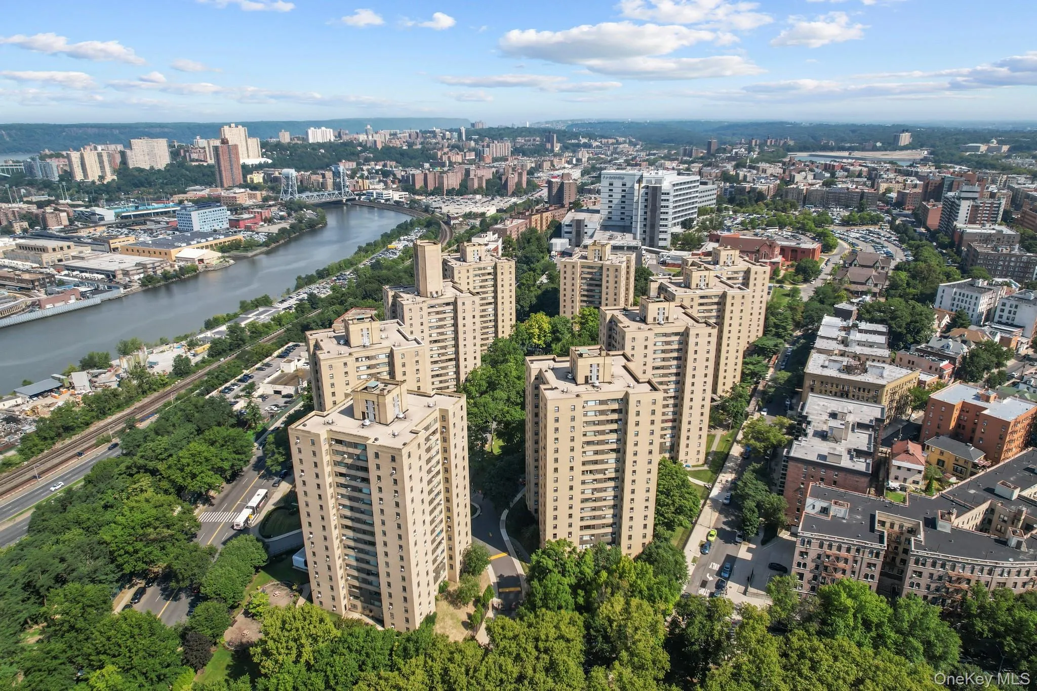 Aerial perspective showcasing a cluster of mid-rise residential towers surrounded by mature landscaping and tree canopy Aerial perspective showcasing a cluster of mid-rise residential towers surrounded by mature landscaping and tree canopy