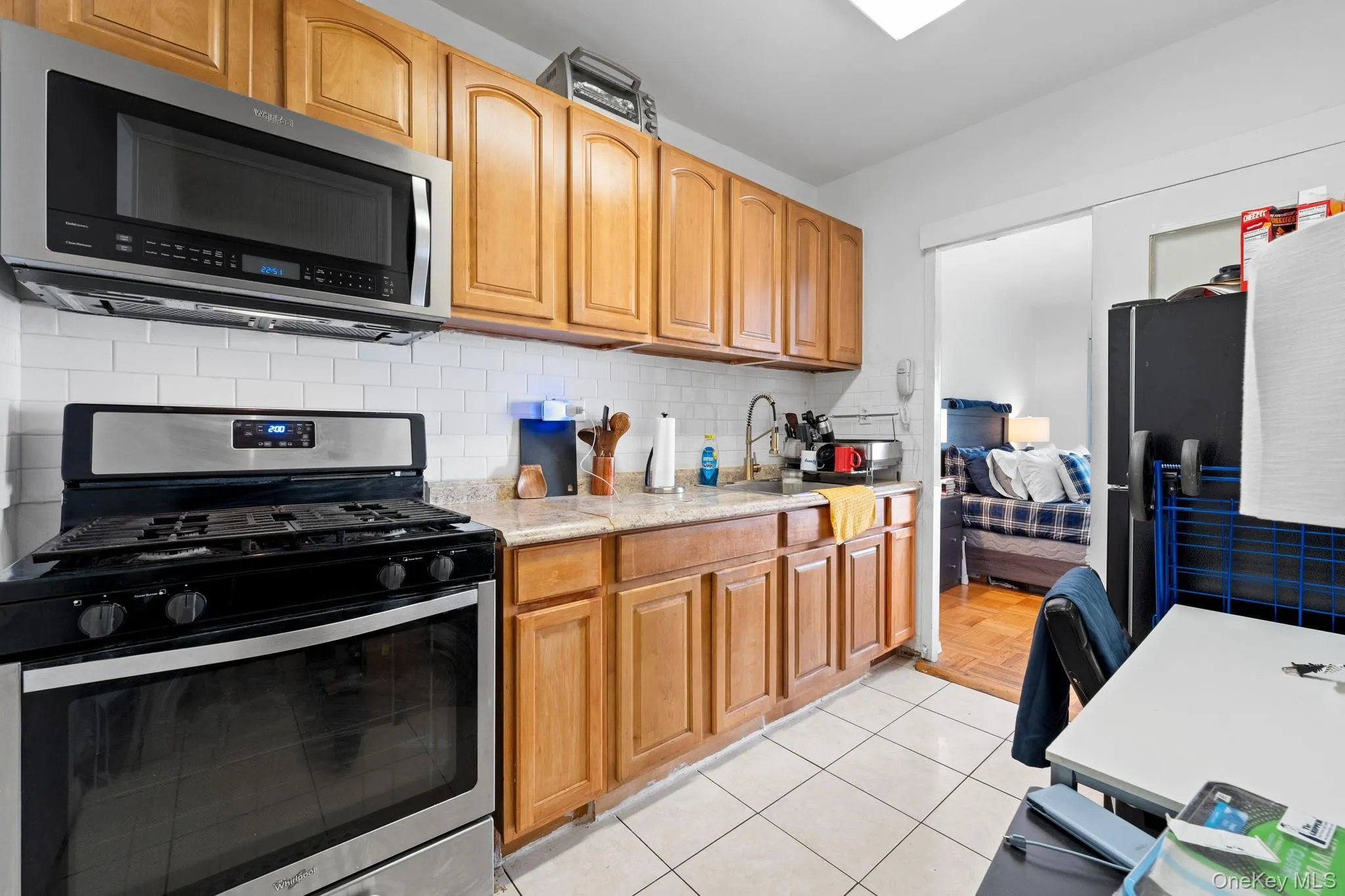 Kitchen featuring wood-finish cabinetry, stainless steel appliances, white subway tile backsplash, and light-colored countertops Kitchen featuring wood-finish cabinetry, stainless steel appliances, white subway tile backsplash, and light-colored countertops
