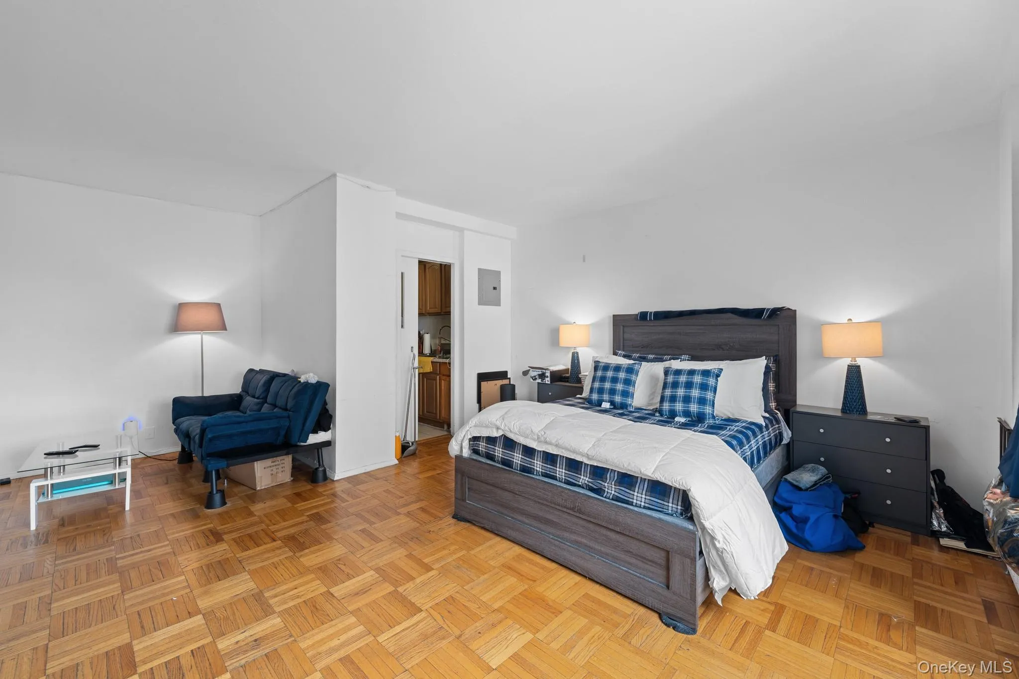Parquet wood flooring throughout, white wall finishes, and a partial view of kitchen cabinetry Parquet wood flooring throughout, white wall finishes, and a partial view of kitchen cabinetry