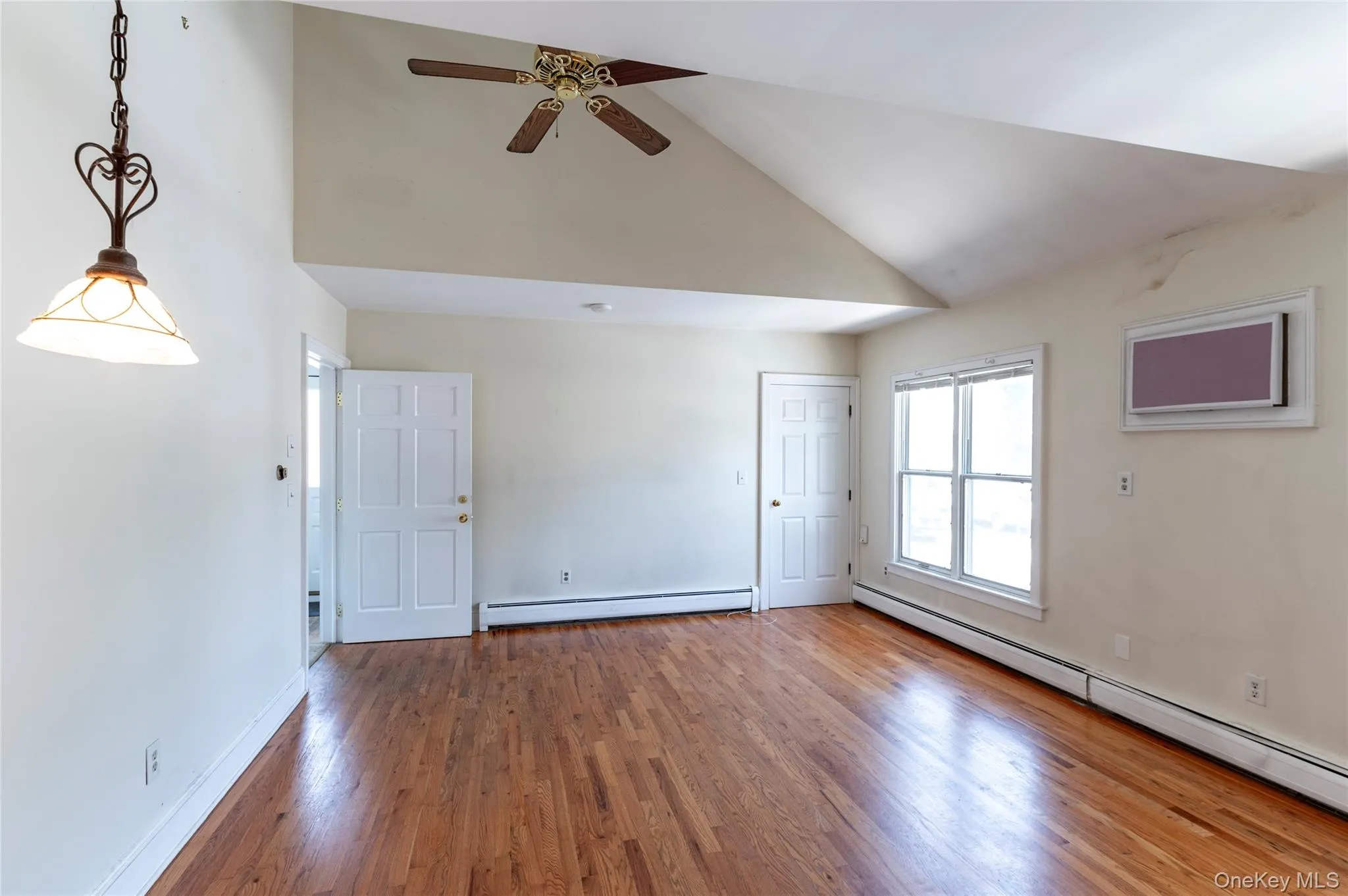 Unfurnished living room with a baseboard heating unit, a ceiling fan, wood finished floors, and high vaulted ceiling Unfurnished living room with a baseboard heating unit, a ceiling fan, wood finished floors, and high vaulted ceiling