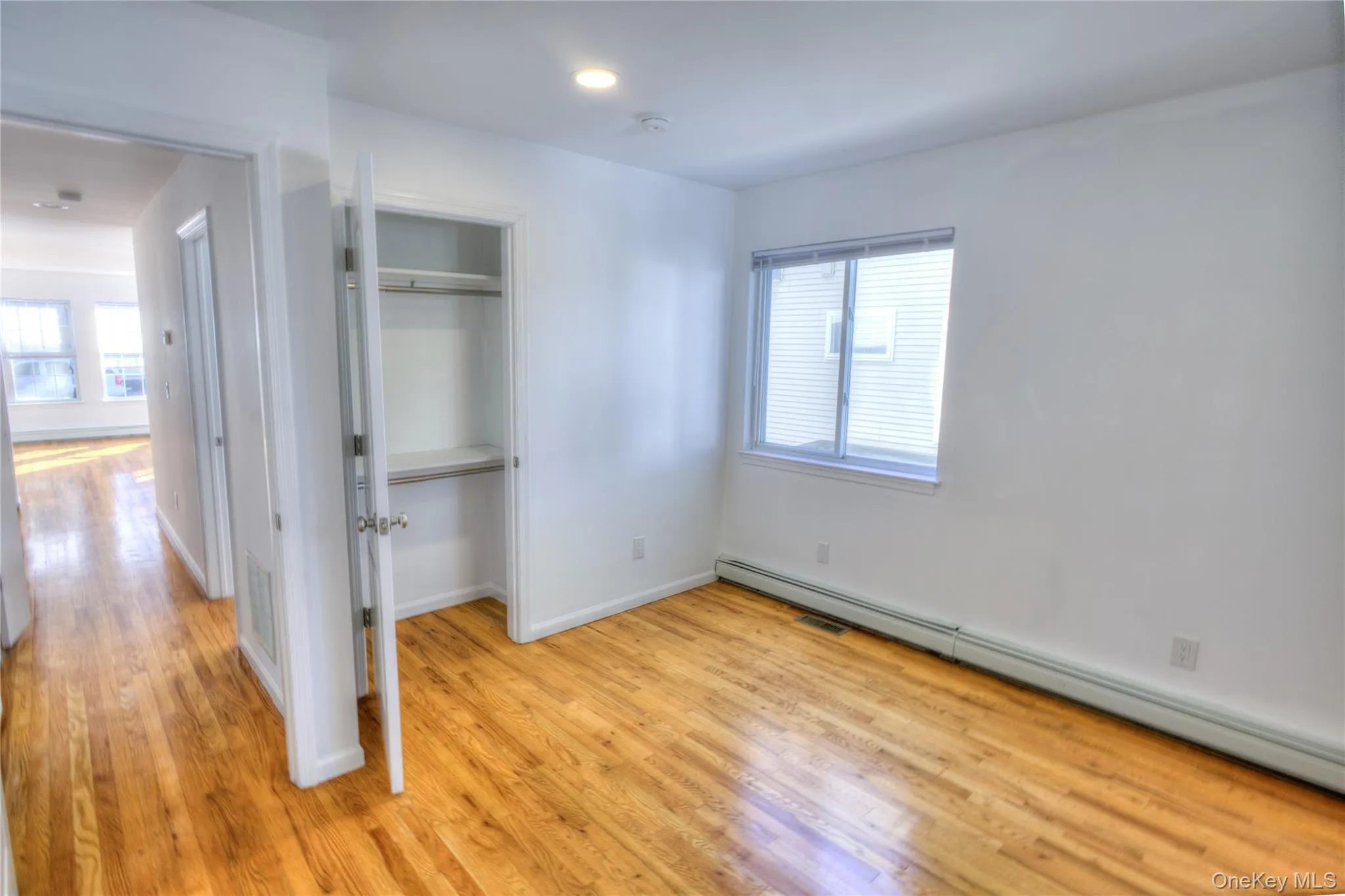 Hardwood flooring, recessed lighting, white walls, and a built-in closet with shelving Hardwood flooring, recessed lighting, white walls, and a built-in closet with shelving