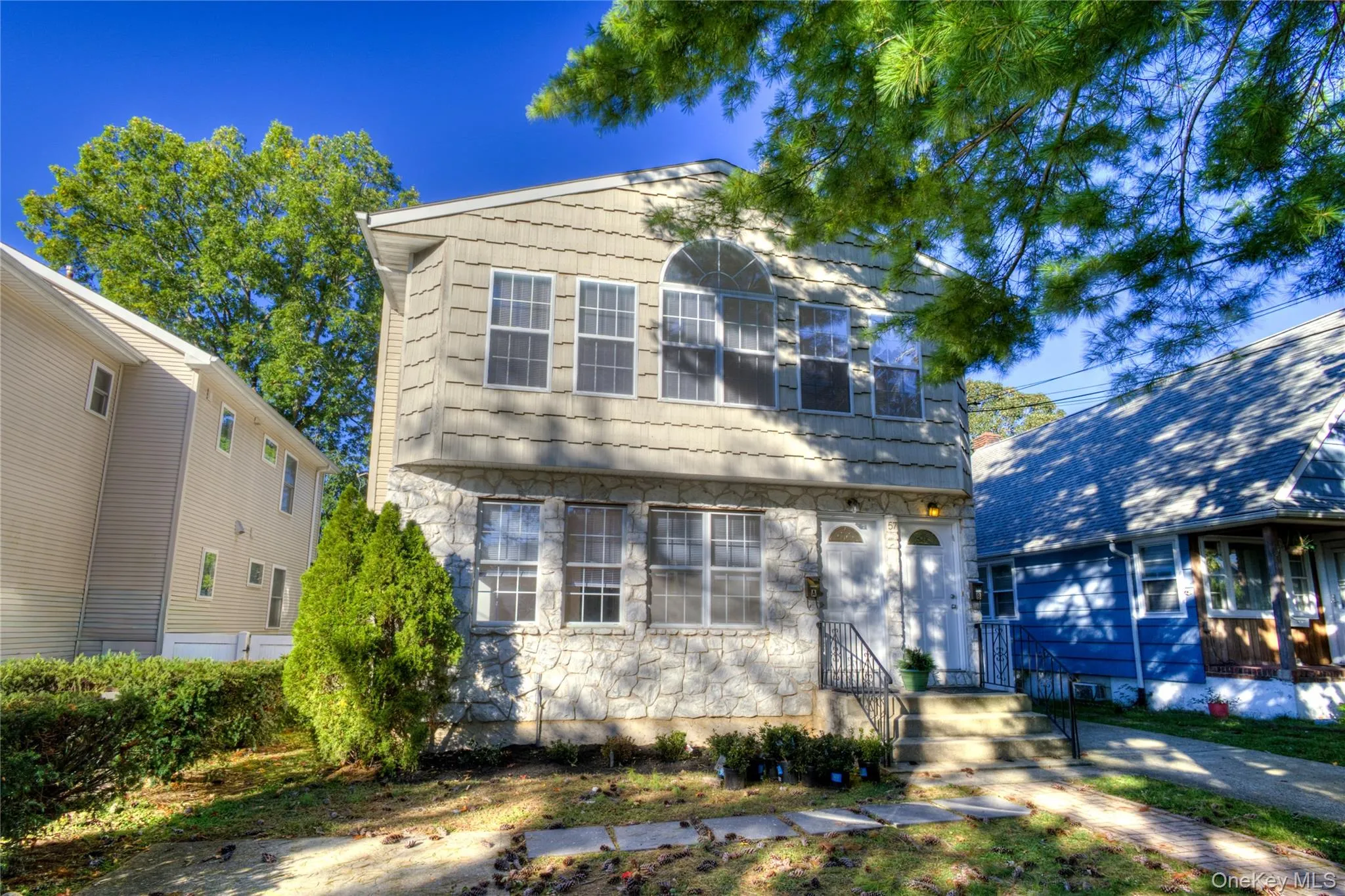 Two-story exterior with stone and shingle siding, multiple windows, and a front entry with steps Two-story exterior with stone and shingle siding, multiple windows, and a front entry with steps