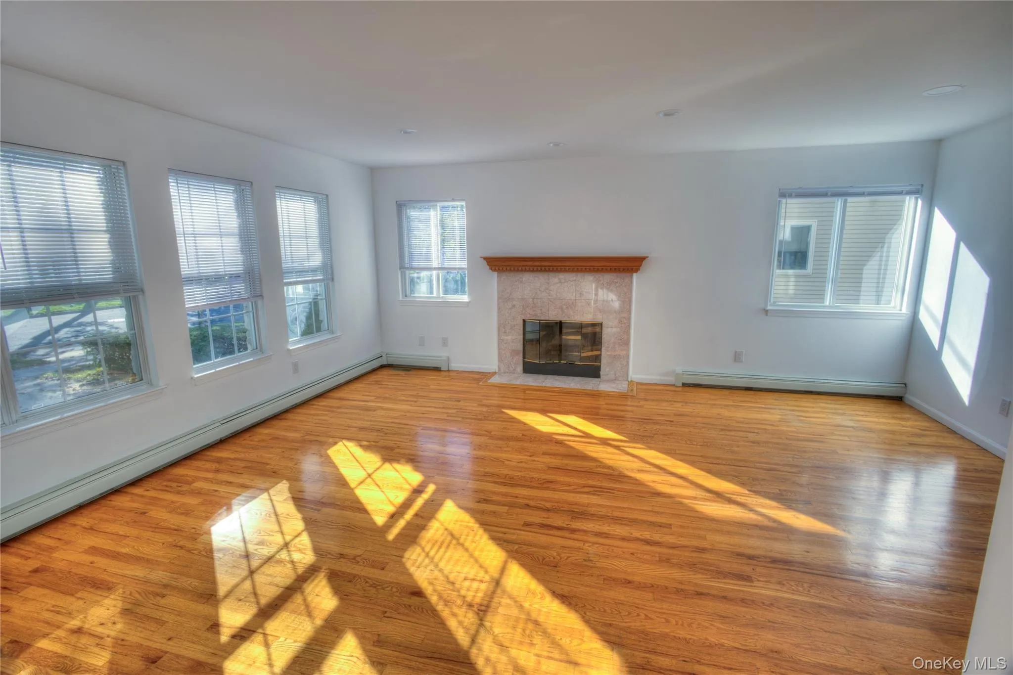 Hardwood flooring, recessed lighting, multiple windows, fireplace with stone surround, and wood mantel Hardwood flooring, recessed lighting, multiple windows, fireplace with stone surround, and wood mantel