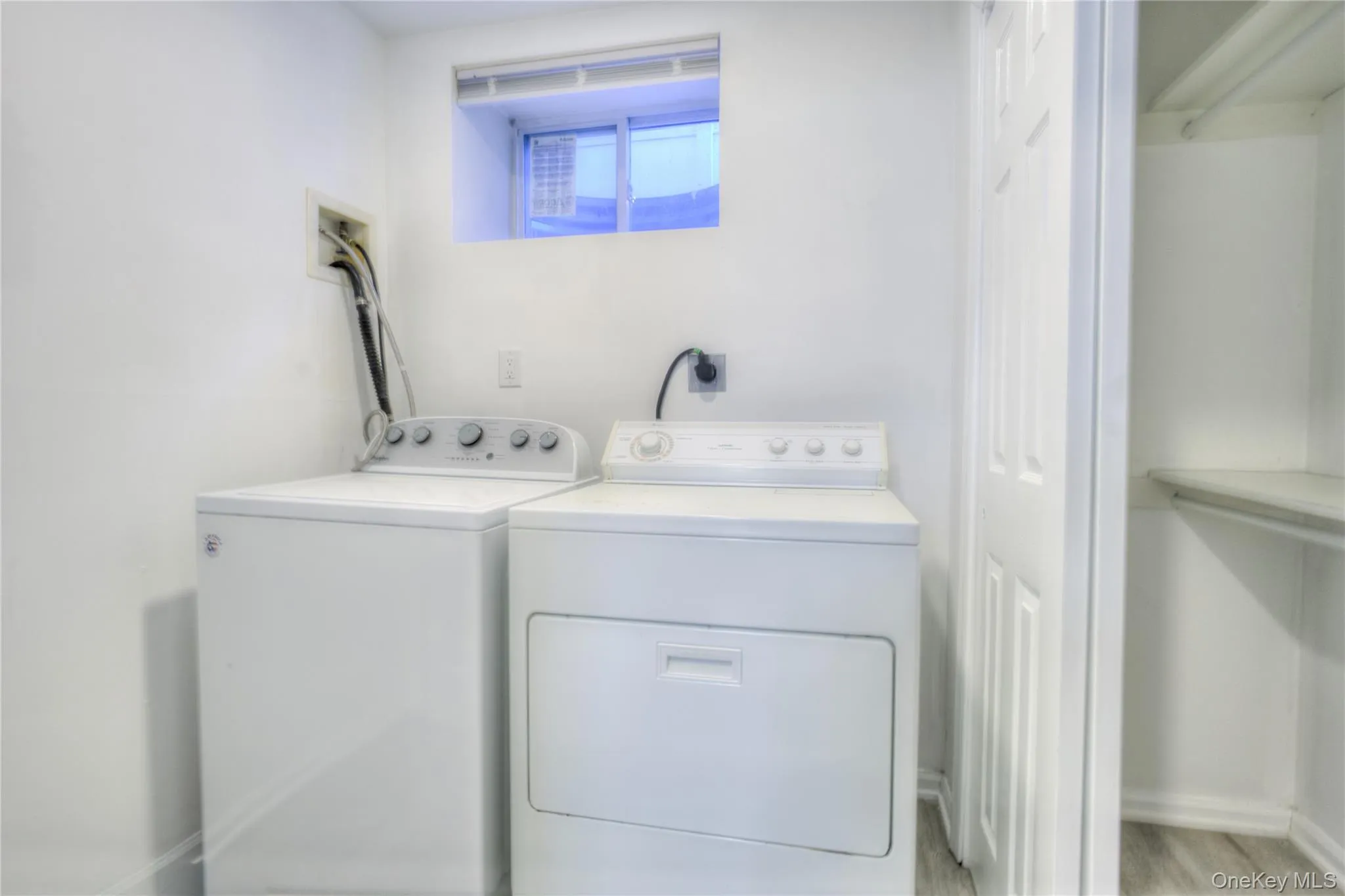 Dedicated laundry area featuring a window, built-in shelving, and wood-finish flooring Dedicated laundry area featuring a window, built-in shelving, and wood-finish flooring