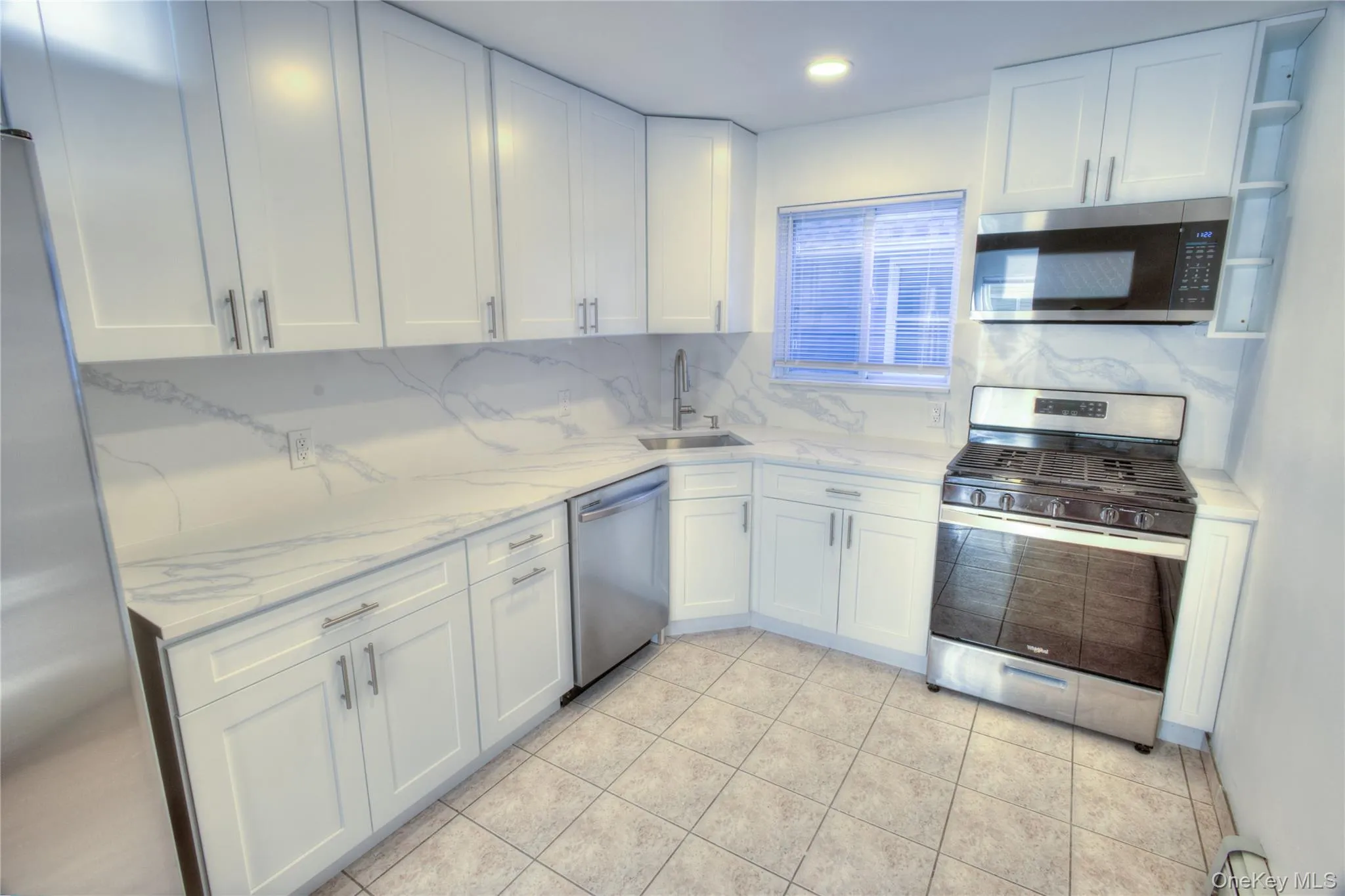Newly Renovated 2026 White shaker-style cabinetry, stainless steel appliances, patterned tile flooring, white countertops, and a white tile backsplash Newly Renovated 2026 White shaker-style cabinetry, stainless steel appliances, patterned tile flooring, white countertops, and a white tile backsplash