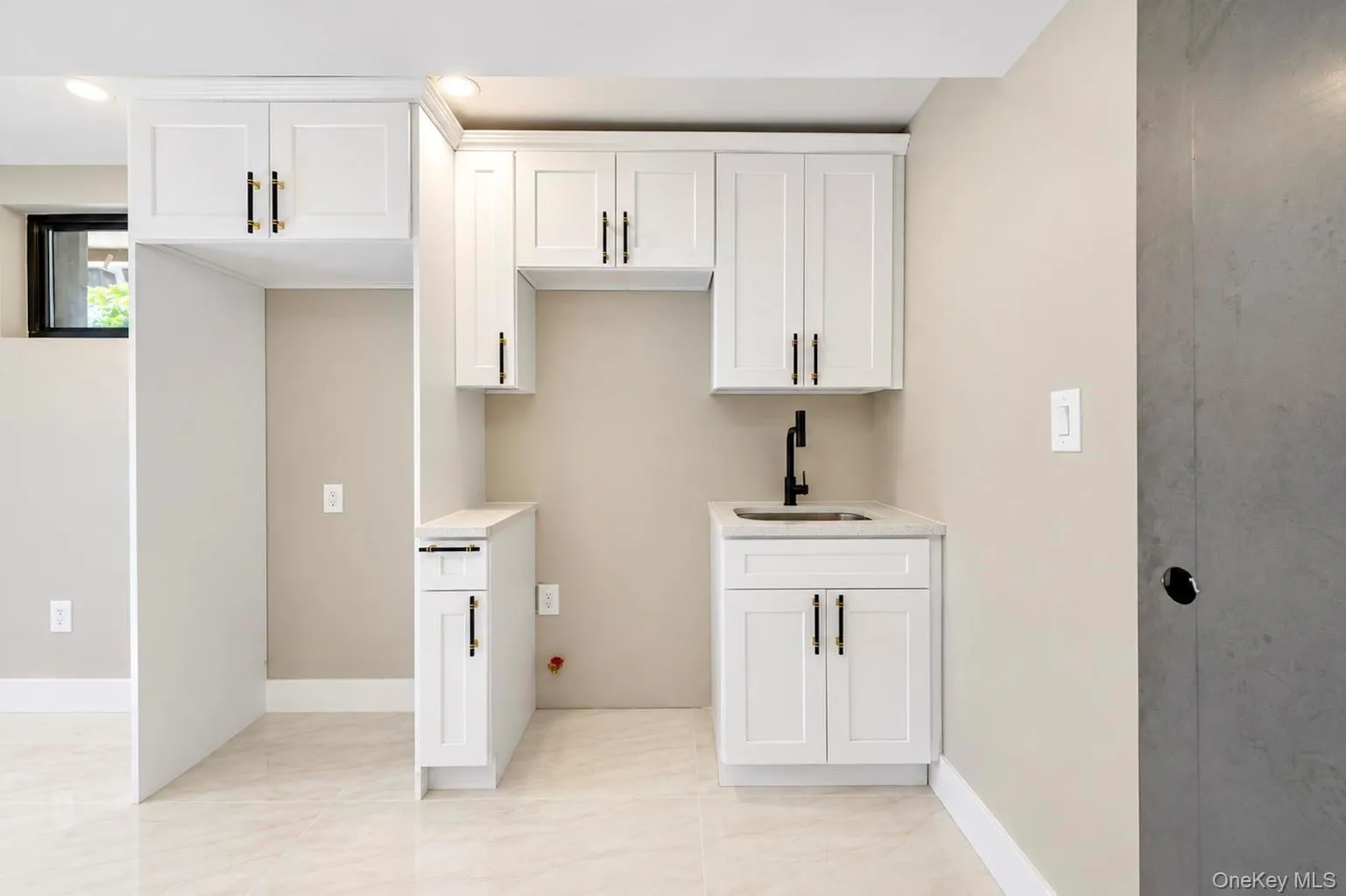 White shaker cabinetry, black hardware, integrated sink, matte black faucet, and light-toned flooring/ White shaker cabinetry, black hardware, integrated sink, matte black faucet, and light-toned flooring/