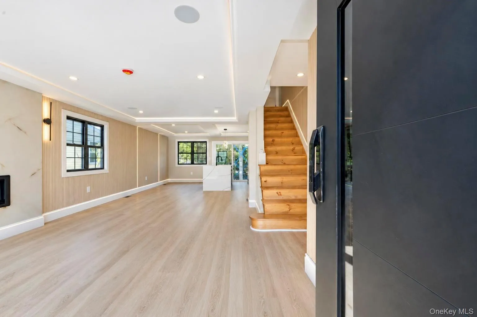 Recessed lighting and ceiling soffits, wood-finish flooring, black-framed windows, built-in wall sconces, and natural wood staircase Recessed lighting and ceiling soffits, wood-finish flooring, black-framed windows, built-in wall sconces, and natural wood staircase