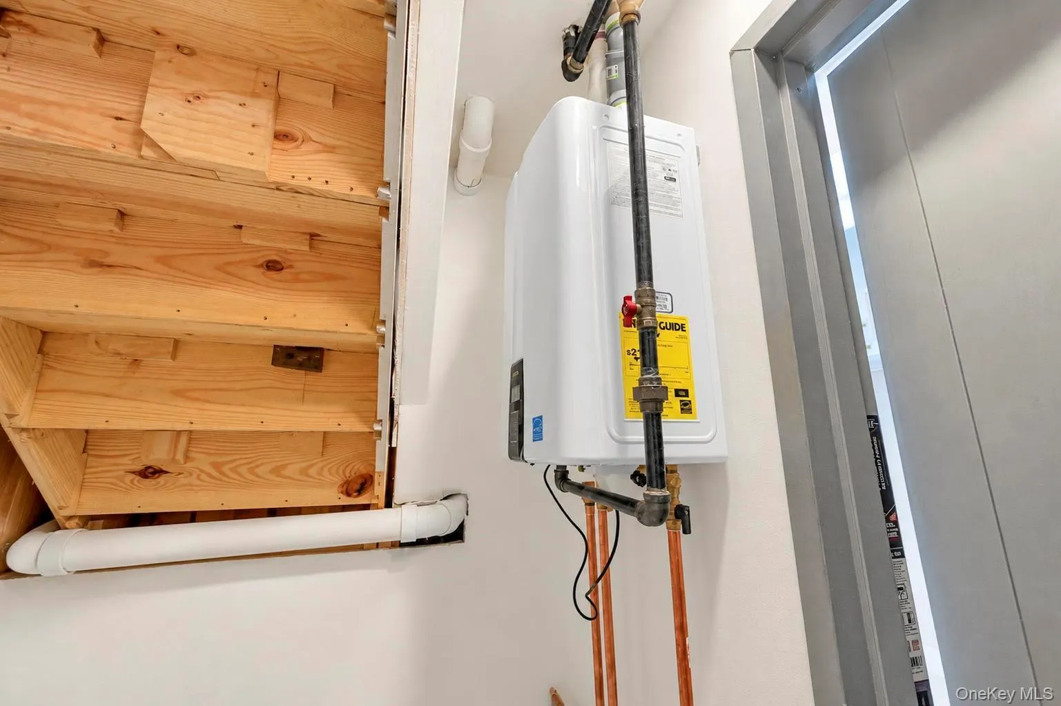 Tankless water heater with exposed copper piping. Tankless water heater with exposed copper piping.