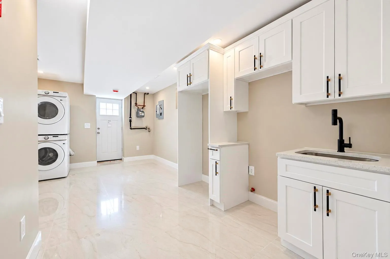 White shaker-style cabinetry, a stainless steel sink with a matte black faucet, and a light-toned countertop. White shaker-style cabinetry, a stainless steel sink with a matte black faucet, and a light-toned countertop.