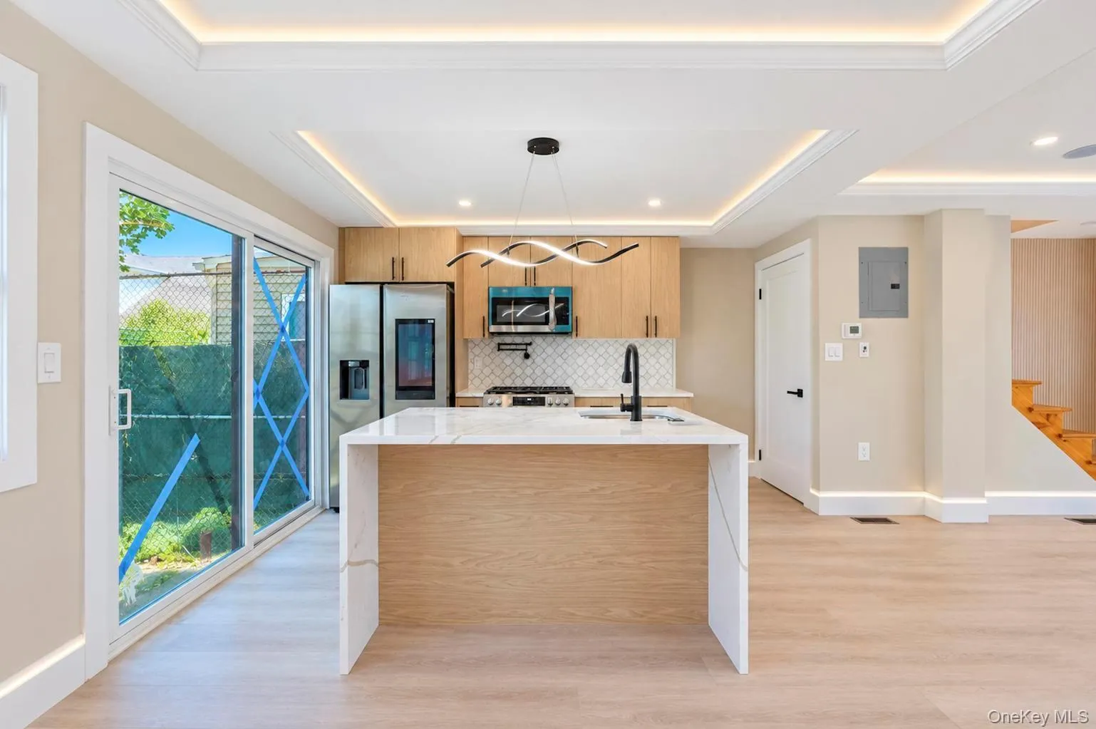 Modern kitchen featuring a waterfall island with a countertop, stainless steel appliances, and wood-finish cabinetry Modern kitchen featuring a waterfall island with a countertop, stainless steel appliances, and wood-finish cabinetry