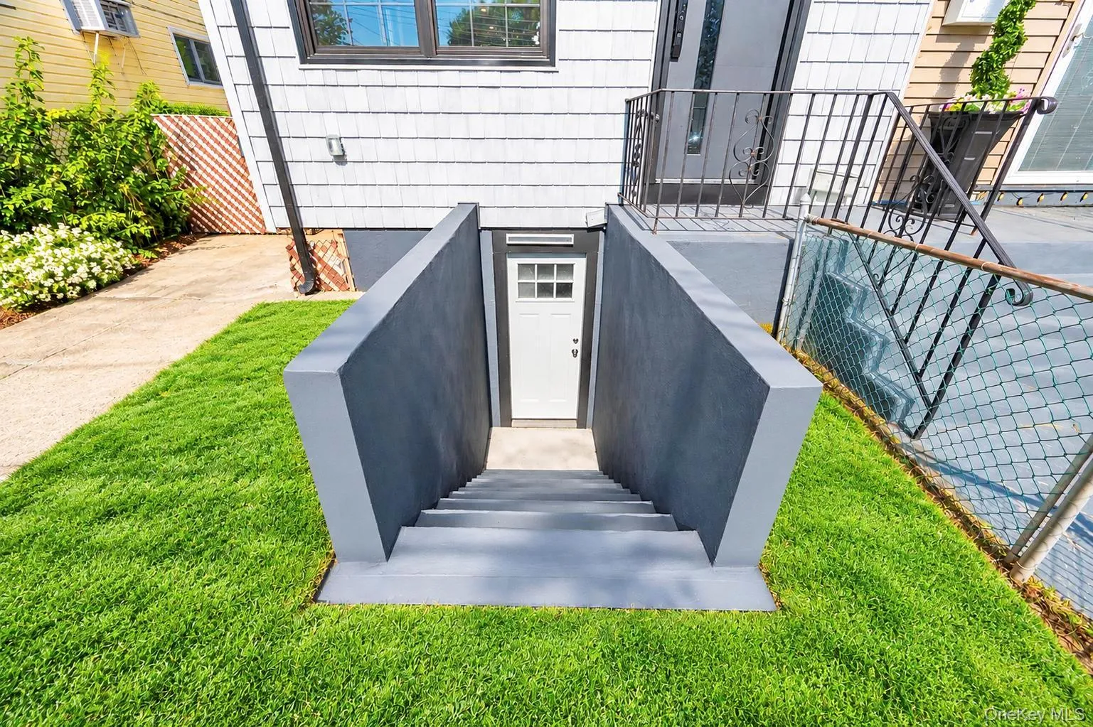 Lower-level entry with concrete steps and retaining walls, surrounded by a manicured lawn Lower-level entry with concrete steps and retaining walls, surrounded by a manicured lawn