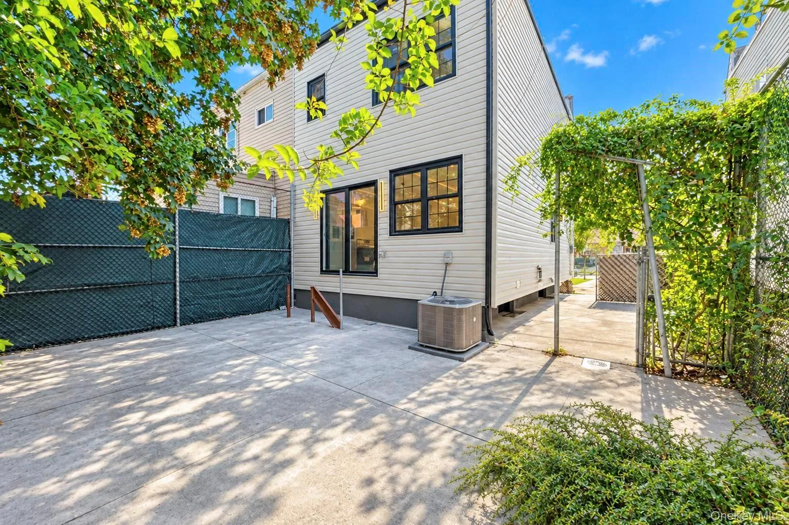 Rear exterior featuring light-colored siding, black-framed windows, and a concrete patio Rear exterior featuring light-colored siding, black-framed windows, and a concrete patio