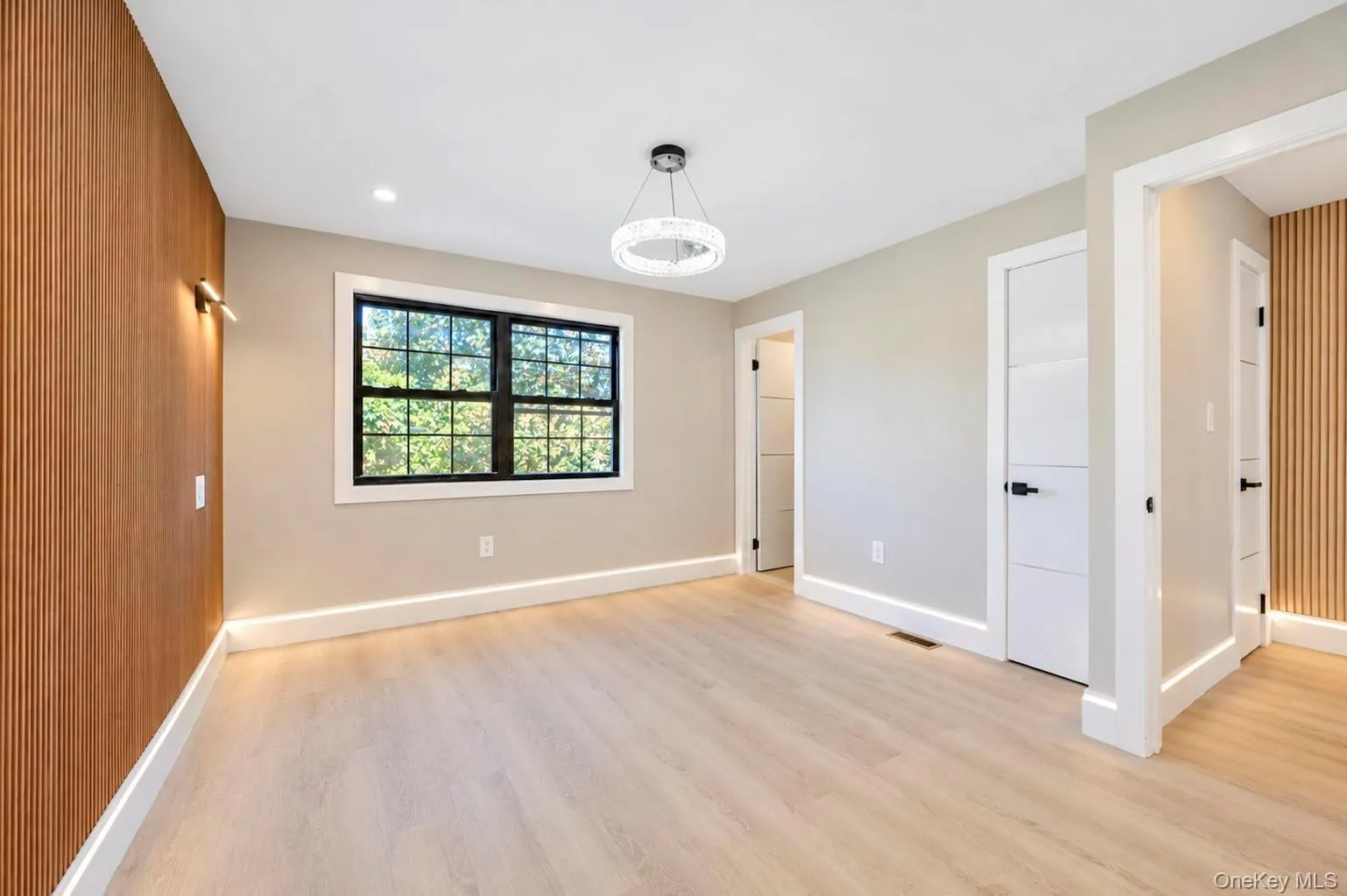 Light wood-finished flooring with recessed lighting and a contemporary chandelier Light wood-finished flooring with recessed lighting and a contemporary chandelier