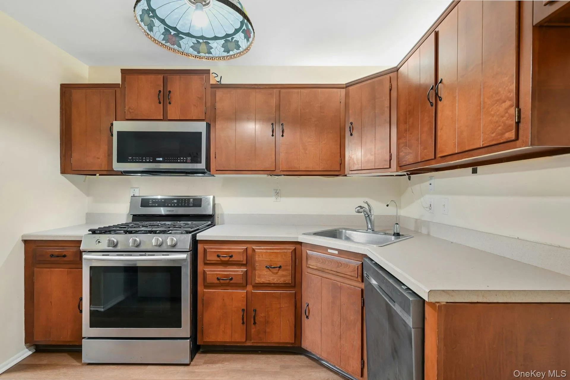 Kitchen with appliances with stainless steel finishes, light countertops, and brown cabinets Kitchen with appliances with stainless steel finishes, light countertops, and brown cabinets