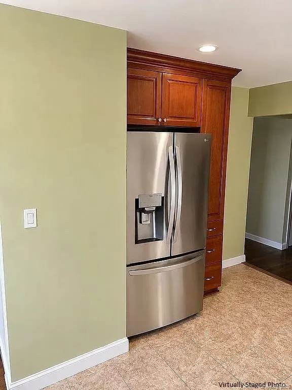 Stainless steel refrigerator with bottom-mount freezer, integrated into built-in wood-finish cabinetry with crown molding and recessed lighting Stainless steel refrigerator with bottom-mount freezer, integrated into built-in wood-finish cabinetry with crown molding and recessed lighting