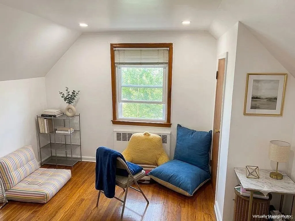 Sloped ceiling architecture featuring wood-finish flooring, a centrally positioned window with wood trim, and recessed lighting Sloped ceiling architecture featuring wood-finish flooring, a centrally positioned window with wood trim, and recessed lighting