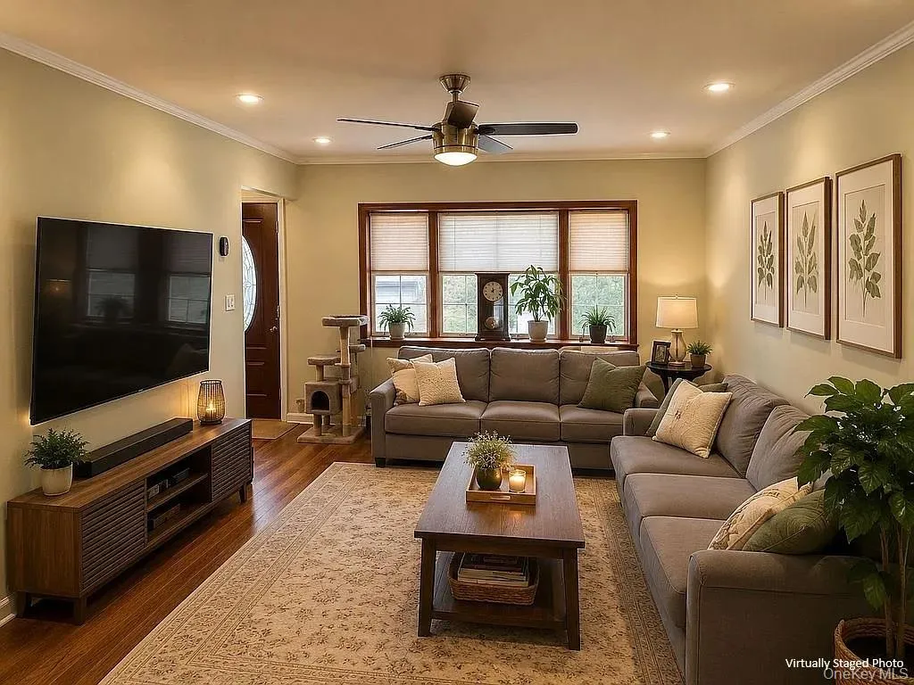 Living area featuring wood-finish flooring, recessed lighting, crown molding, and a multi-panel window configuration with dark wood trim Living area featuring wood-finish flooring, recessed lighting, crown molding, and a multi-panel window configuration with dark wood trim