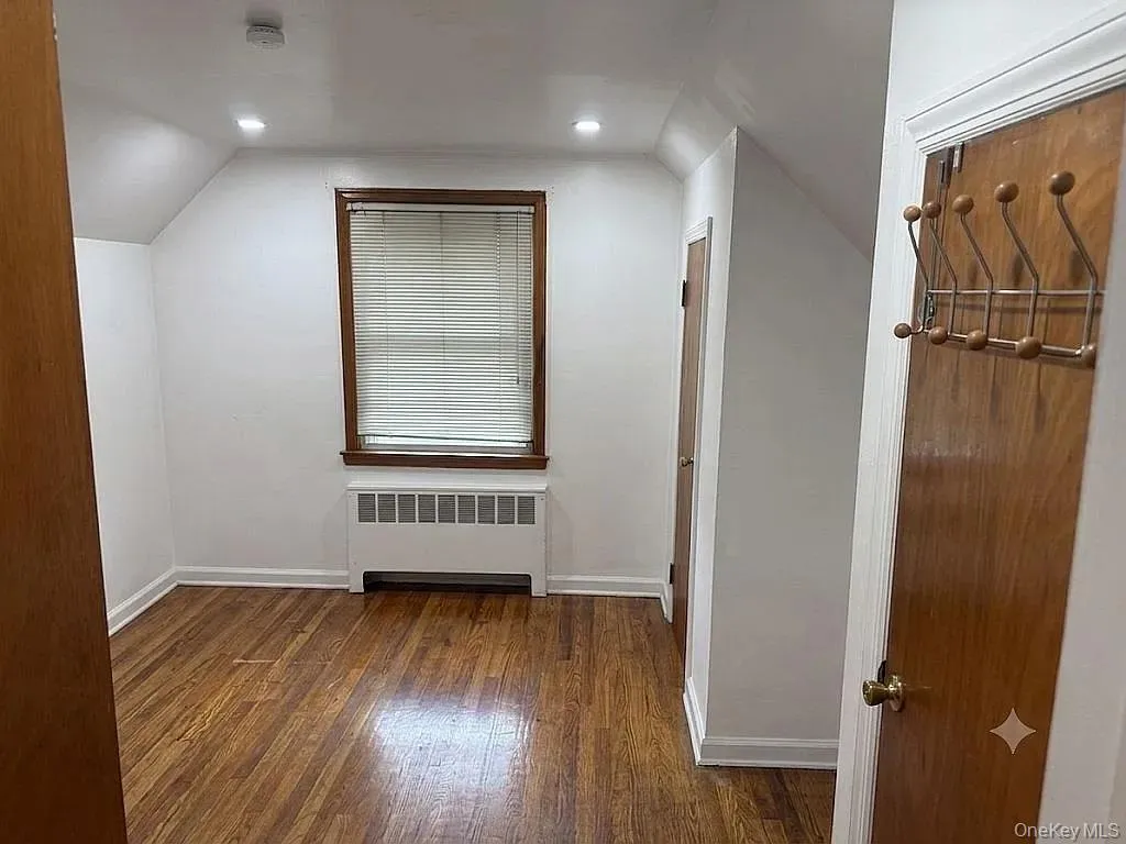 Room featuring wood-finish flooring, recessed lighting, and a single window with wood trim Room featuring wood-finish flooring, recessed lighting, and a single window with wood trim
