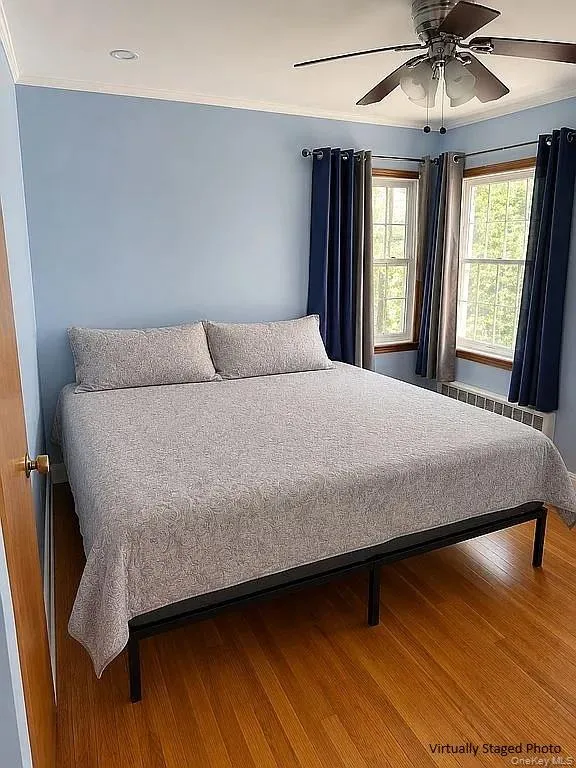 Wood-finish flooring, dual windows with wood trim, and a ceiling fan with integrated lighting Wood-finish flooring, dual windows with wood trim, and a ceiling fan with integrated lighting