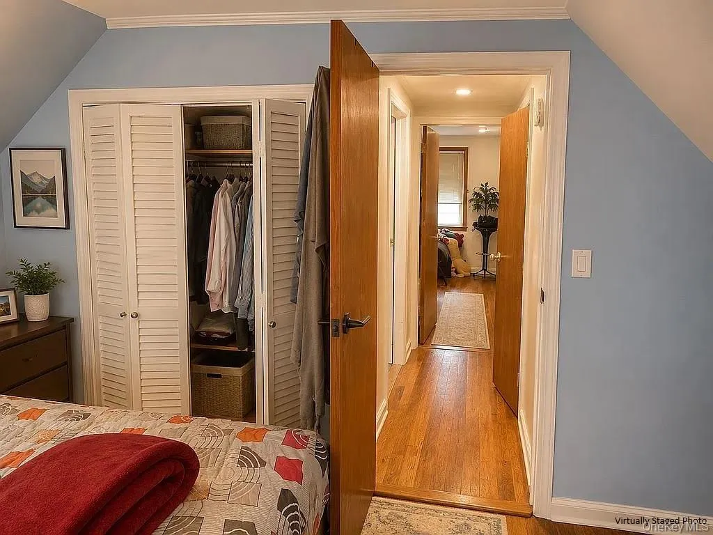 Wood-finish flooring, white louvered-door closet with built-in shelving, solid wood interior doors, and crown molding Wood-finish flooring, white louvered-door closet with built-in shelving, solid wood interior doors, and crown molding