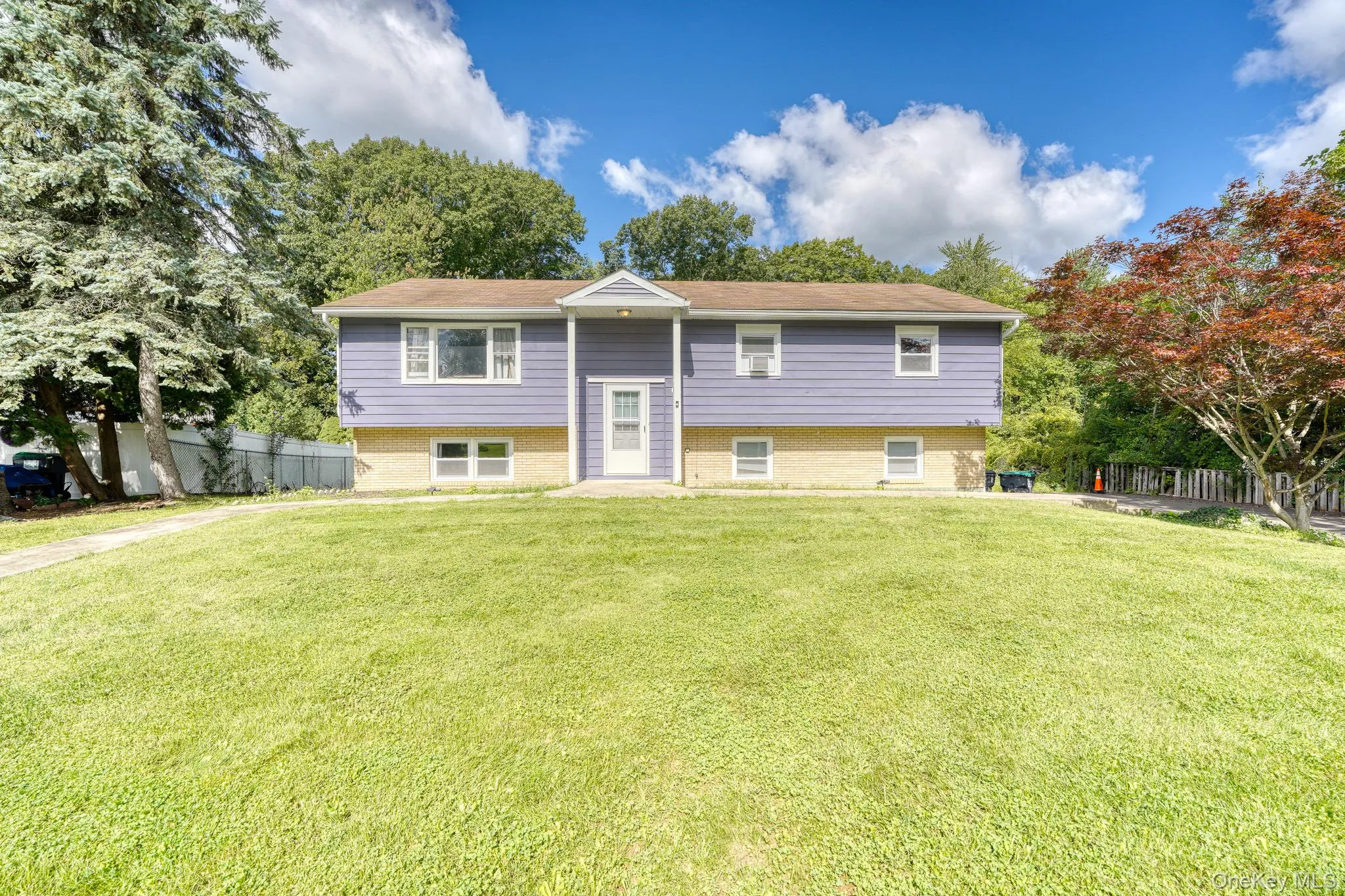 Beautiful split-level home with a modern purple exterior and light brick foundation, set on a spacious, well-manicured lawn. The symmetrical façade features a central entryway with a covered portico framed by white trim and columns, adding timeless curb appeal. Large windows allow natural light to fill the interior, while mature trees and landscaped greenery provide a serene backdrop. This inviting property combines classic design with contemporary color for a standout look in a peaceful suburban setting. Beautiful split-level home with a modern purple exterior and light brick foundation, set on a spacious, well-manicured lawn. The symmetrical façade features a central entryway with a covered portico framed by white trim and columns, adding timeless curb appeal. Large windows allow natural light to fill the interior, while mature trees and landscaped greenery provide a serene backdrop. This inviting property combines classic design with contemporary color for a standout look in a peaceful suburban setting.