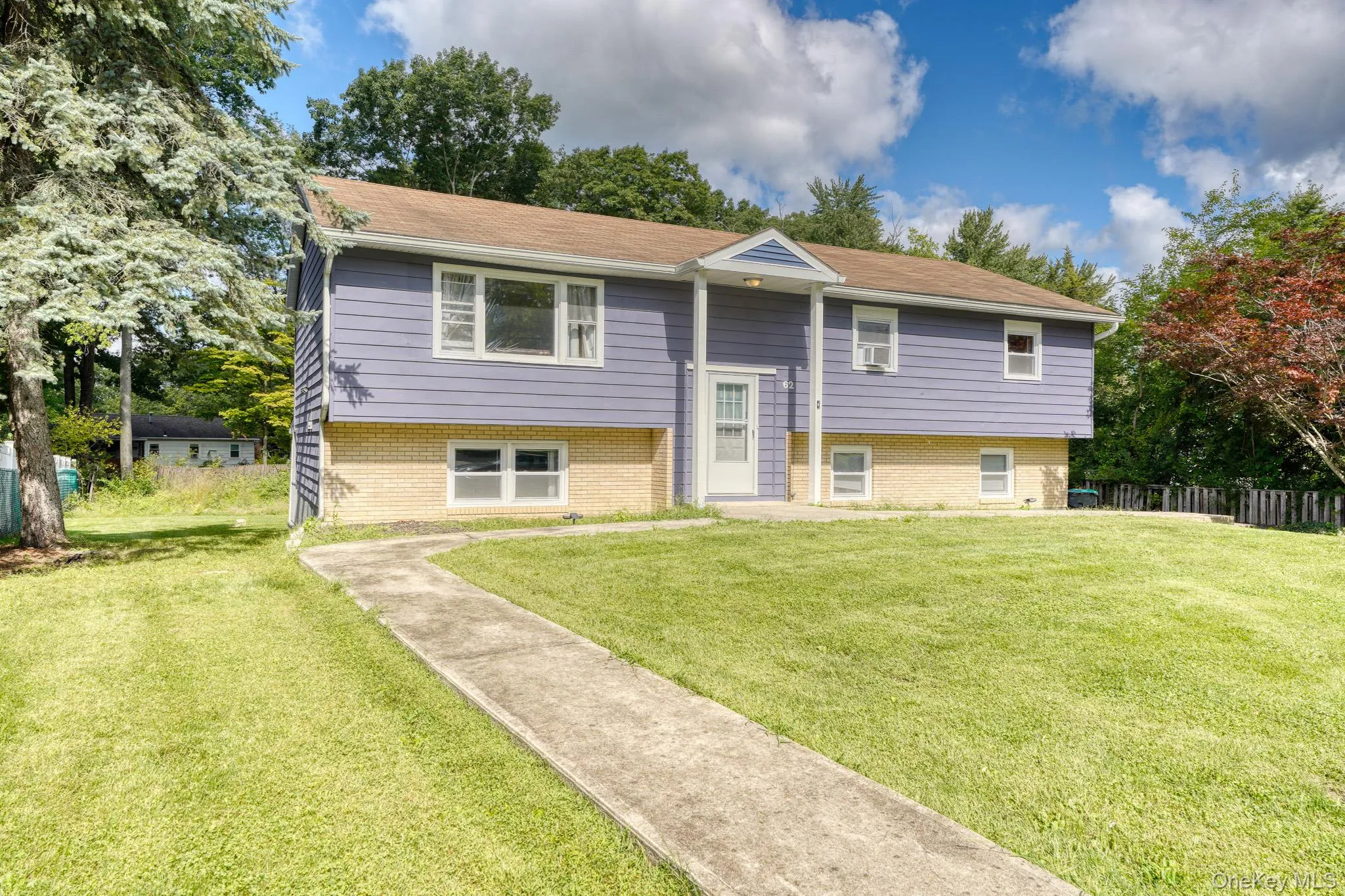 Beautiful split-level home with a welcoming front entrance and manicured lawn. The exterior features a unique combination of soft purple siding and light brickwork, complemented by a brown shingle roof and white trim. A concrete walkway leads to the covered entryway framed by columns, while mature trees and landscaped greenery add curb appeal. Bright and inviting, this home blends classic design with modern color for standout charm. Beautiful split-level home with a welcoming front entrance and manicured lawn. The exterior features a unique combination of soft purple siding and light brickwork, complemented by a brown shingle roof and white trim. A concrete walkway leads to the covered entryway framed by columns, while mature trees and landscaped greenery add curb appeal. Bright and inviting, this home blends classic design with modern color for standout charm.