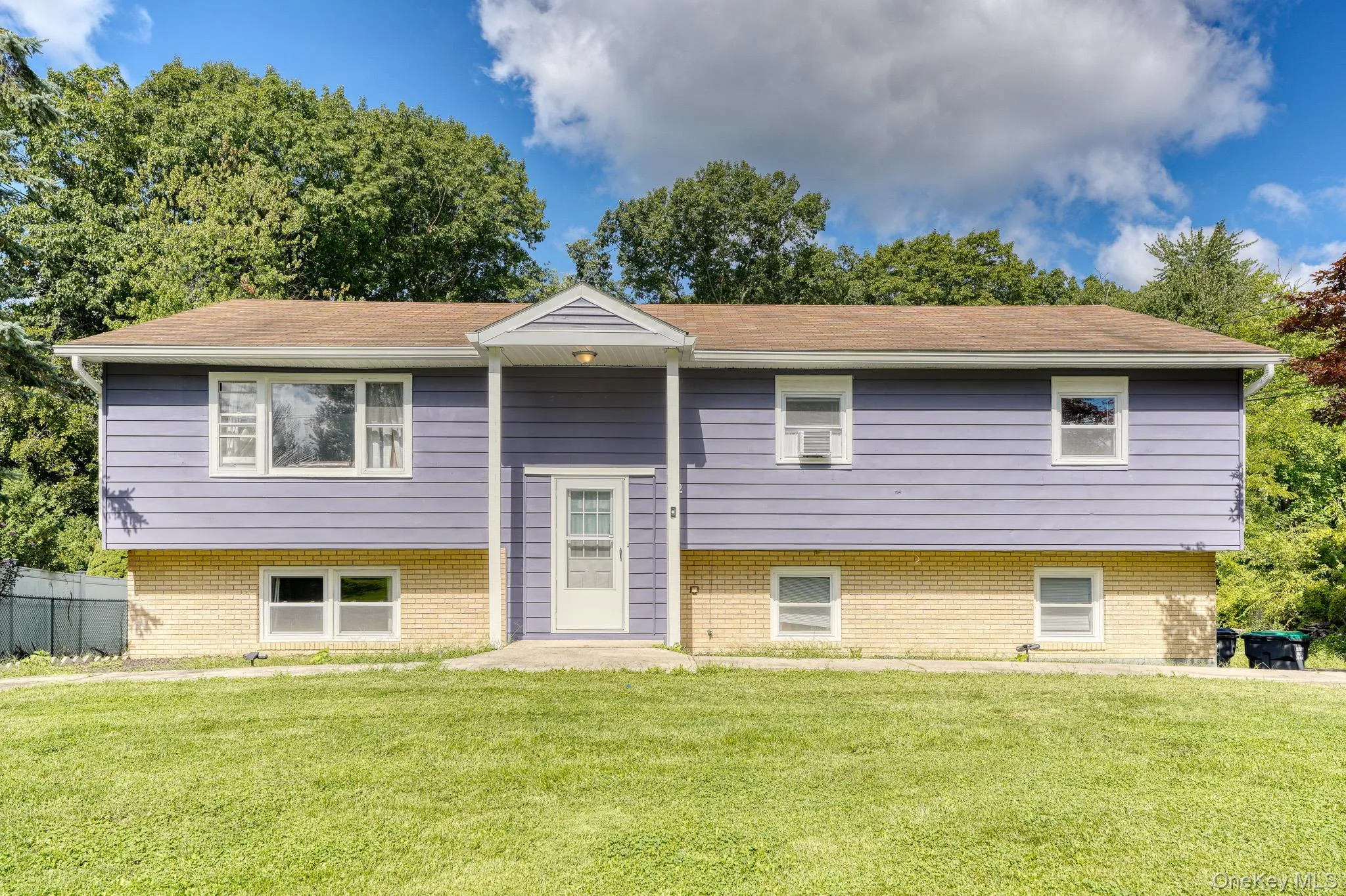 Charming two-story split-level residence showcasing a clean, modern look with purple siding and light brick accents. The symmetrical façade includes multiple windows for natural light and a central entryway with a small portico. Surrounded by lush greenery and a spacious front yard, the property offers a serene suburban setting with timeless appeal and well-maintained landscaping. Charming two-story split-level residence showcasing a clean, modern look with purple siding and light brick accents. The symmetrical façade includes multiple windows for natural light and a central entryway with a small portico. Surrounded by lush greenery and a spacious front yard, the property offers a serene suburban setting with timeless appeal and well-maintained landscaping.