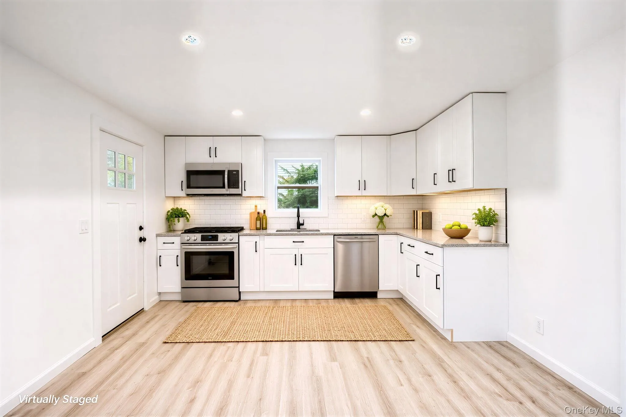 Kitchen featuring white Shaker-style cabinetry, stainless steel appliances, light-toned stone-finish countertops, subway tile backsplash, and vinyl wood-finish flooring *virtually staged Kitchen featuring white Shaker-style cabinetry, stainless steel appliances, light-toned stone-finish countertops, subway tile backsplash, and vinyl wood-finish flooring *virtually staged