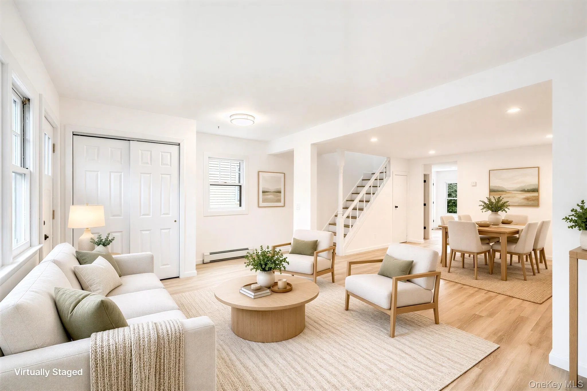 Open-concept interior featuring wood-finish flooring, recessed lighting, double-panel sliding closet doors, and a staircase with white balusters *virtually staged Open-concept interior featuring wood-finish flooring, recessed lighting, double-panel sliding closet doors, and a staircase with white balusters *virtually staged