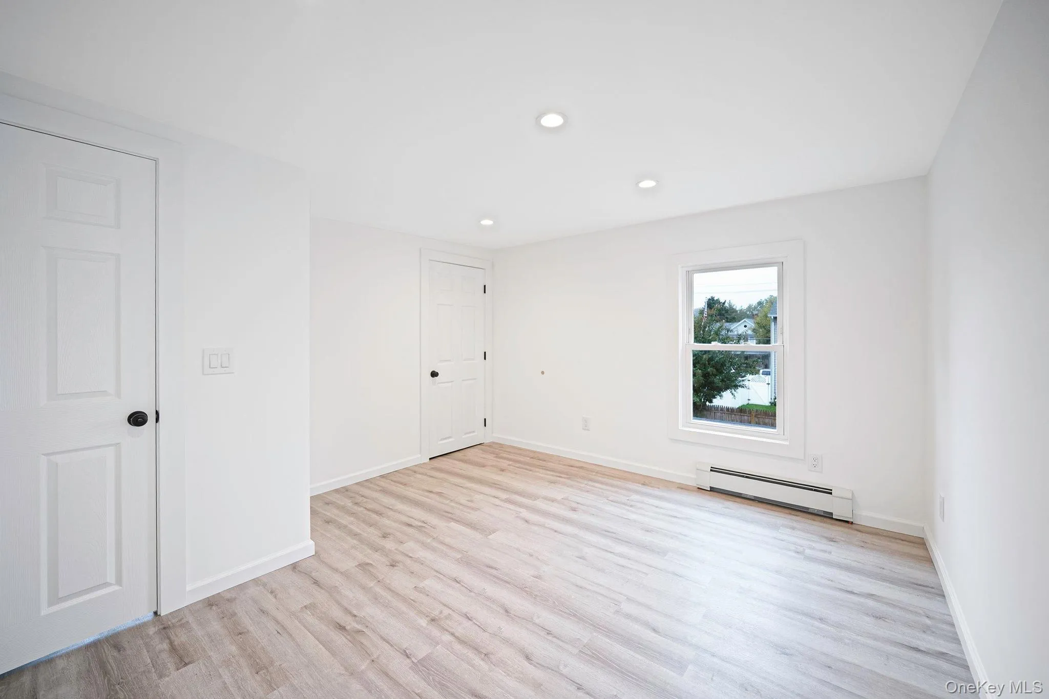 Room featuring vinyl wood-finish flooring, recessed lighting, and white six-panel doors Room featuring vinyl wood-finish flooring, recessed lighting, and white six-panel doors