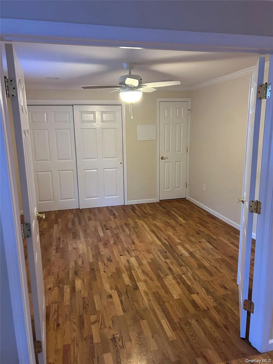 Unfurnished bedroom featuring dark wood finished floors, crown molding, a closet, and a ceiling fan Unfurnished bedroom featuring dark wood finished floors, crown molding, a closet, and a ceiling fan
