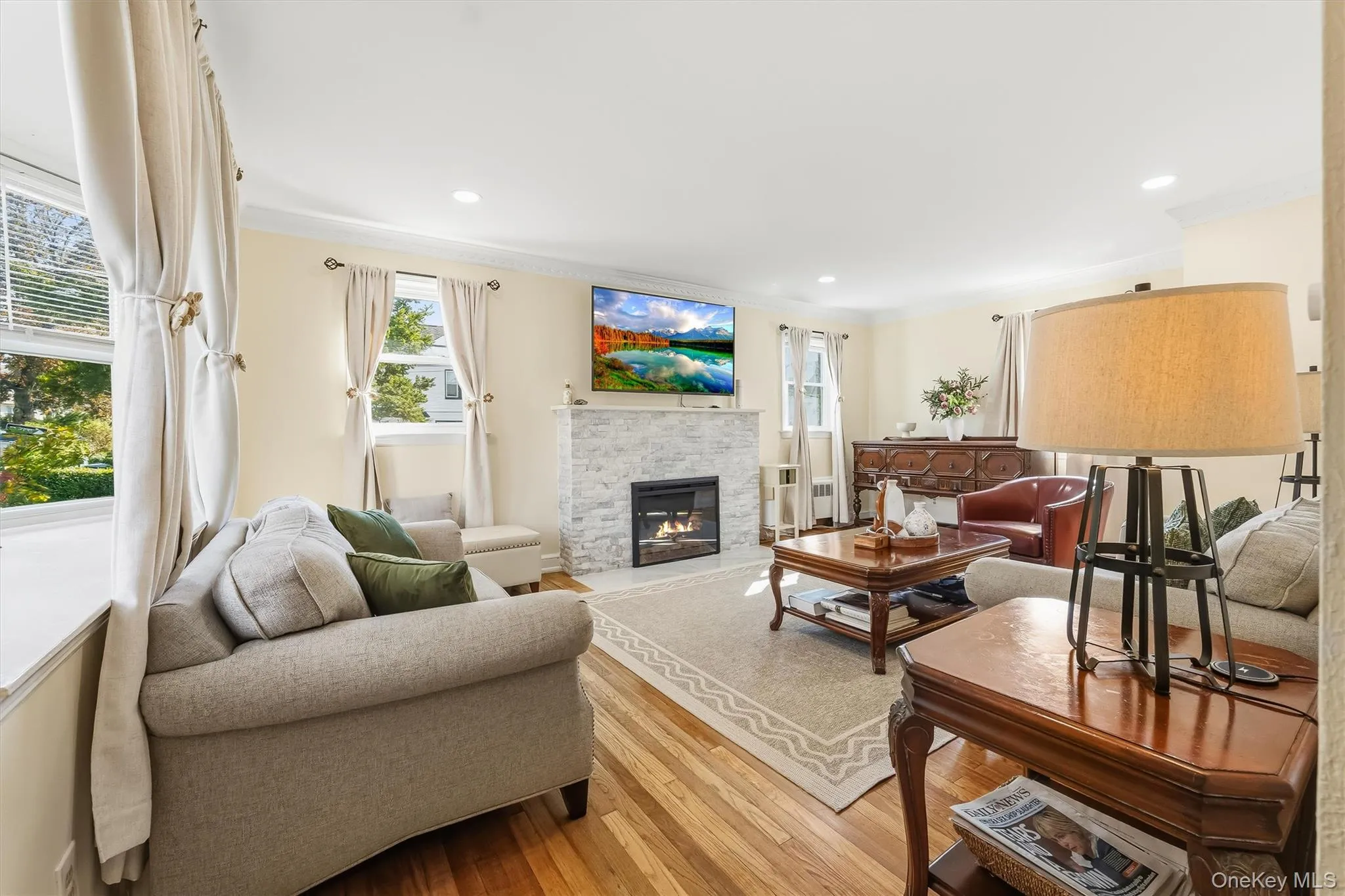 Beautiful hardwood floors, crown molding, recessed lighting, and a contemporary light-stone electric fireplace bring warmth and distinction to this expansive living room. Beautiful hardwood floors, crown molding, recessed lighting, and a contemporary light-stone electric fireplace bring warmth and distinction to this expansive living room.