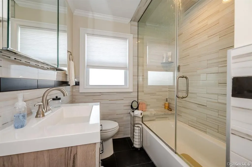 Full bath with combined bath / shower with glass door, vanity, tile walls, and steam shower feature Full bath with combined bath / shower with glass door, vanity, tile walls, and steam shower feature
