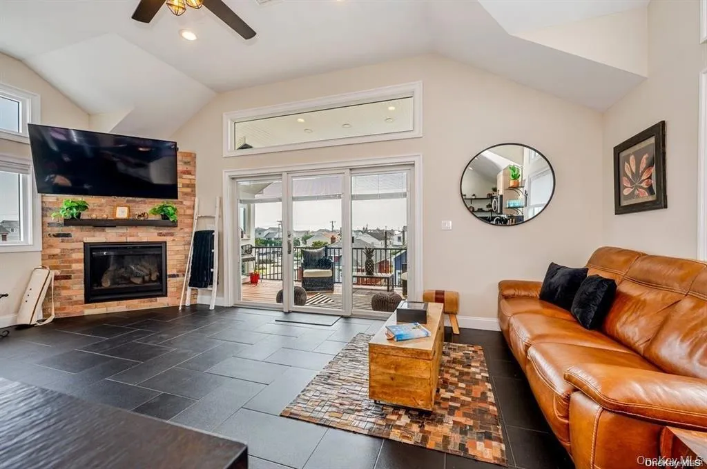 Living area featuring vaulted ceiling, recessed lighting, a ceiling fan, a gas fireplace, and dark tile flooring Living area featuring vaulted ceiling, recessed lighting, a ceiling fan, a gas fireplace, and dark tile flooring