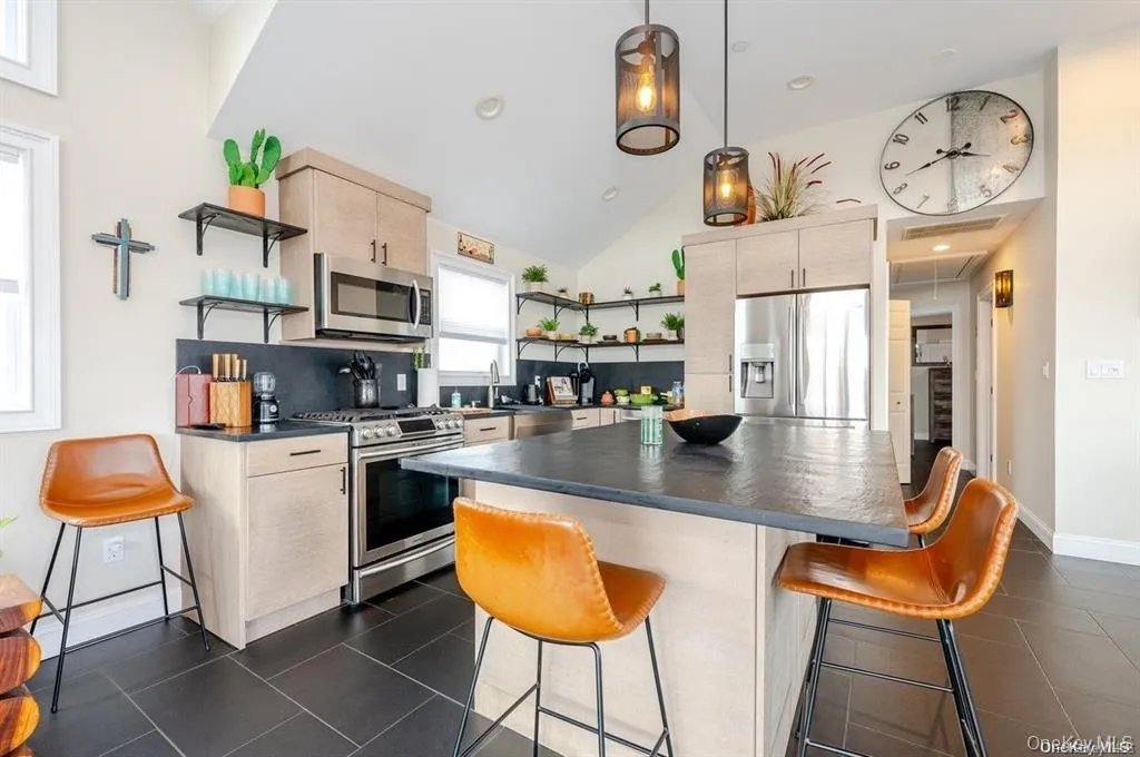 Kitchen featuring open shelves, a breakfast bar, stainless steel appliances, dark countertops, and a center island Kitchen featuring open shelves, a breakfast bar, stainless steel appliances, dark countertops, and a center island