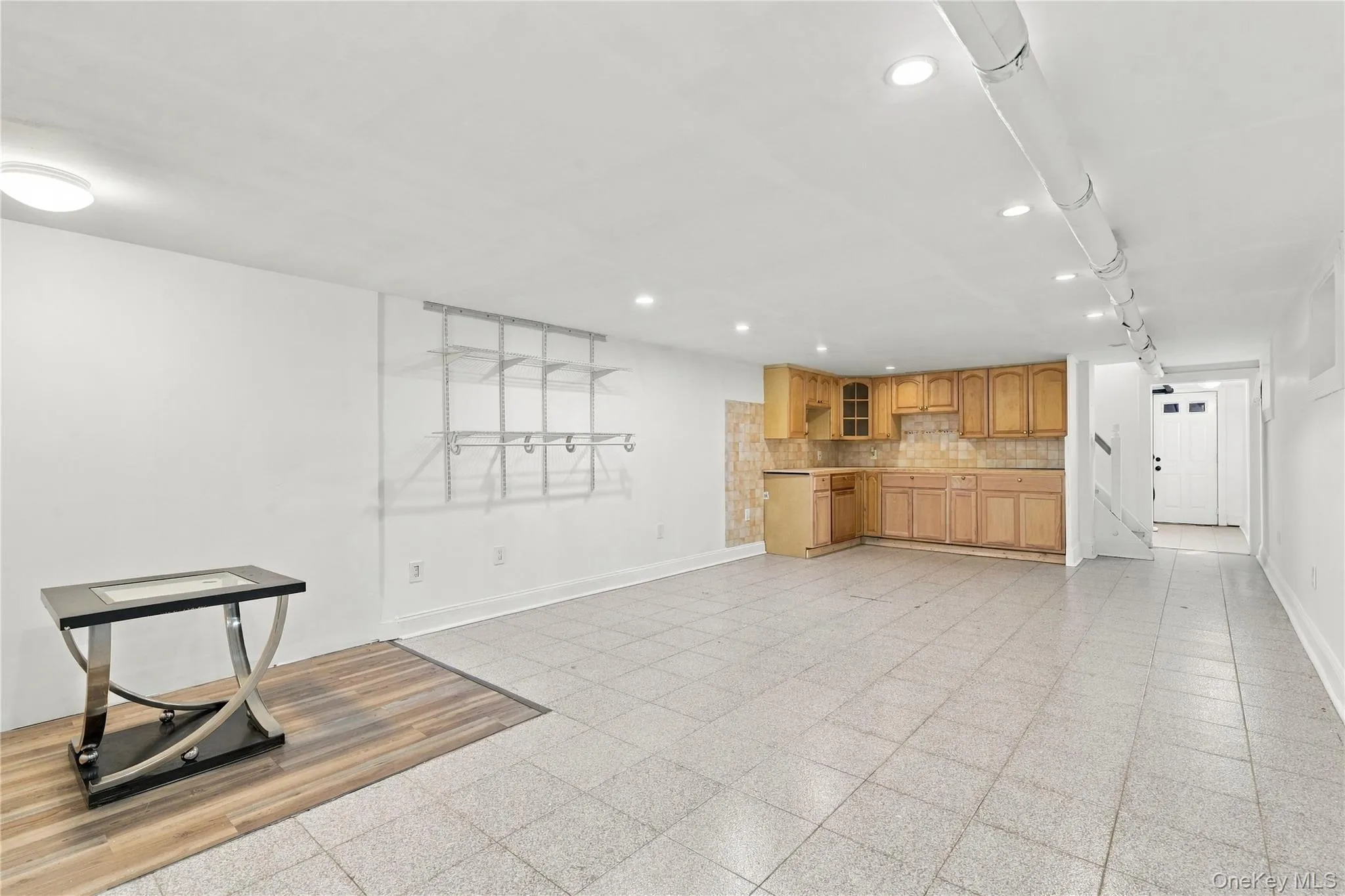 Open floor plan featuring tile flooring, recessed ceiling lighting, light wood cabinetry, and integrated shelving Open floor plan featuring tile flooring, recessed ceiling lighting, light wood cabinetry, and integrated shelving
