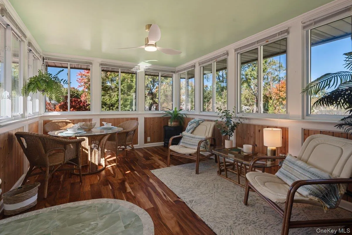 A stunning three-season sunroom with windows and wood-paneled walls, custom tile entry, and a ceiling fan adds additional living space. A stunning three-season sunroom with windows and wood-paneled walls, custom tile entry, and a ceiling fan adds additional living space.