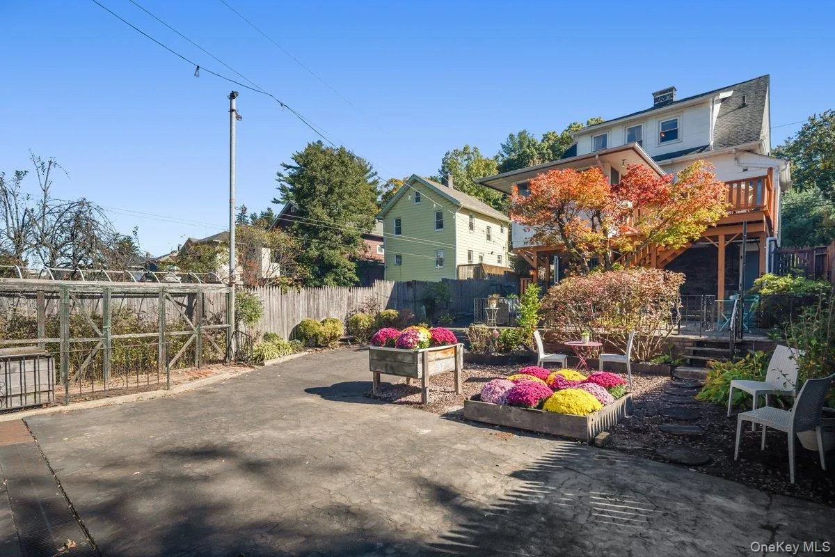 A paved driveway and additional parking are surrounded by backyard gardens. A paved driveway and additional parking are surrounded by backyard gardens.