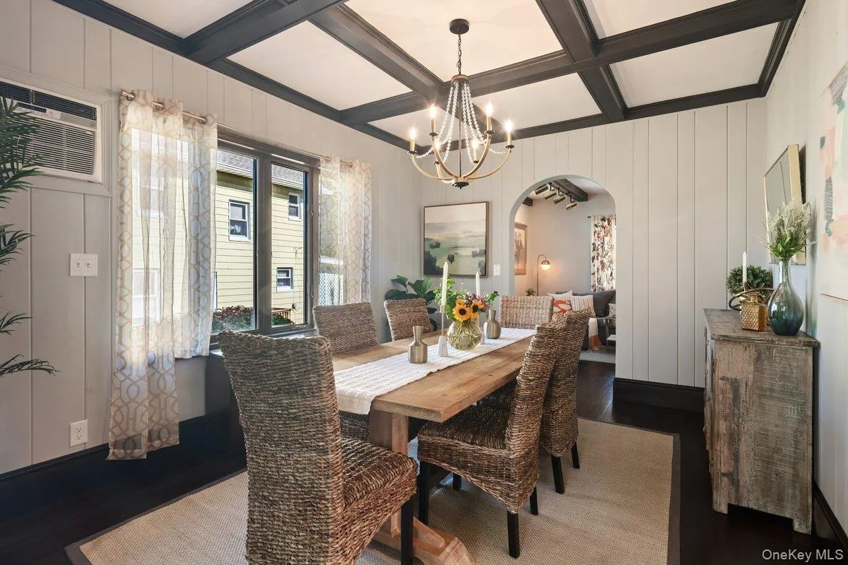 A picture window fills the room with natural sunlight, highlighting the beautiful coffered ceiling and wood-paneled walls, while a novelty chandelier adds warmth and character. A picture window fills the room with natural sunlight, highlighting the beautiful coffered ceiling and wood-paneled walls, while a novelty chandelier adds warmth and character.